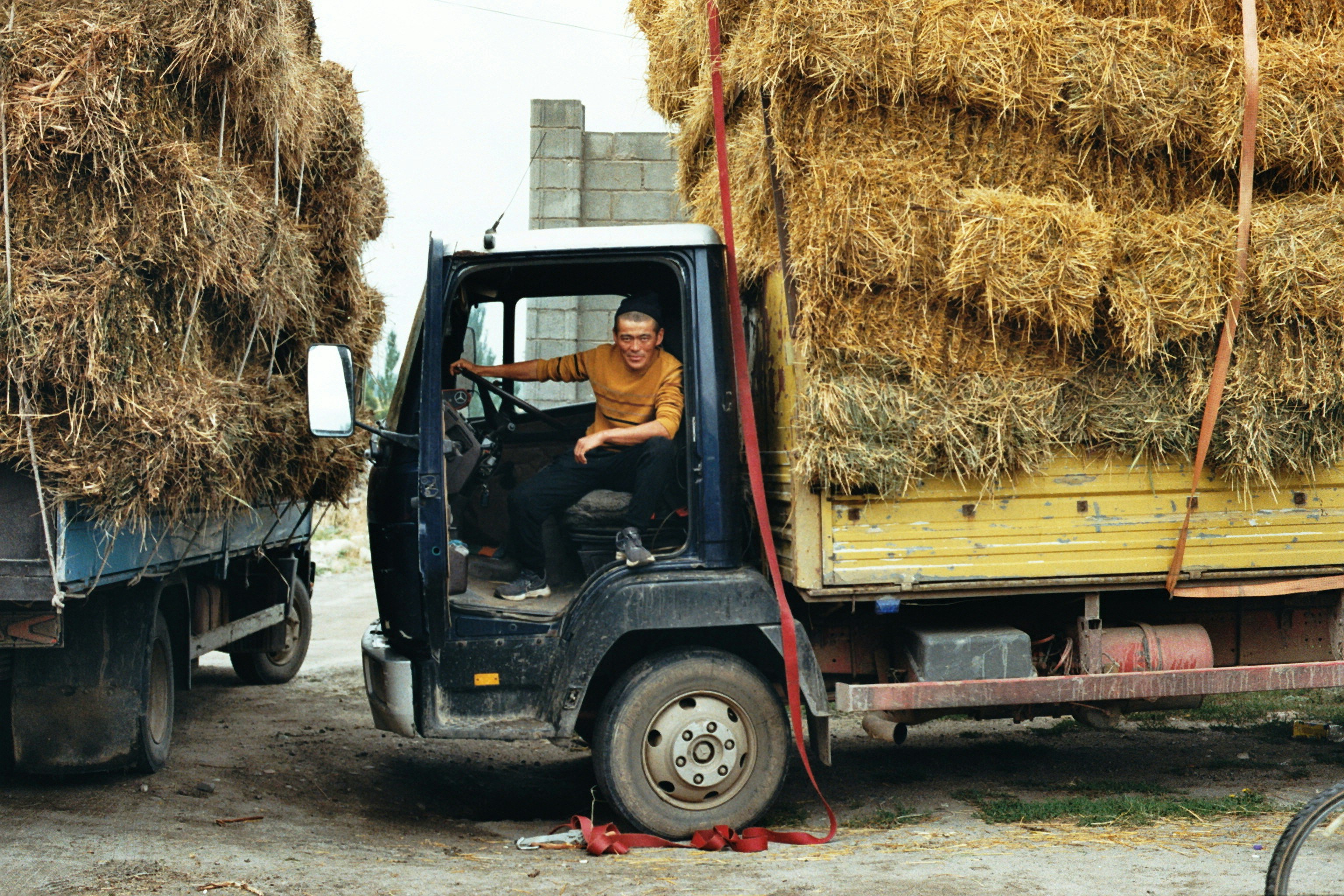 Man sitting in truck loaded with hay bales