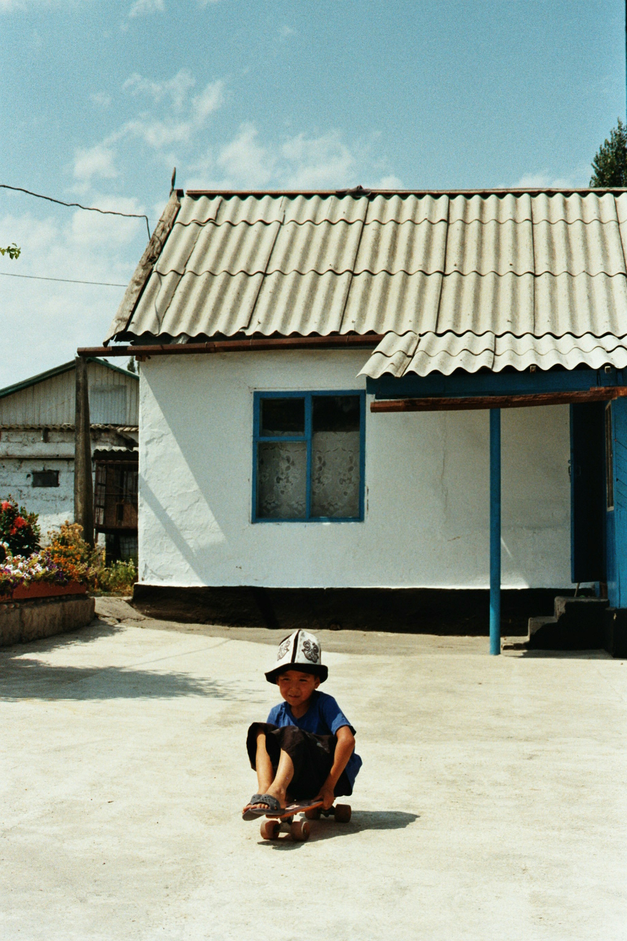 Young boy rides a skateboard in front of a house.
