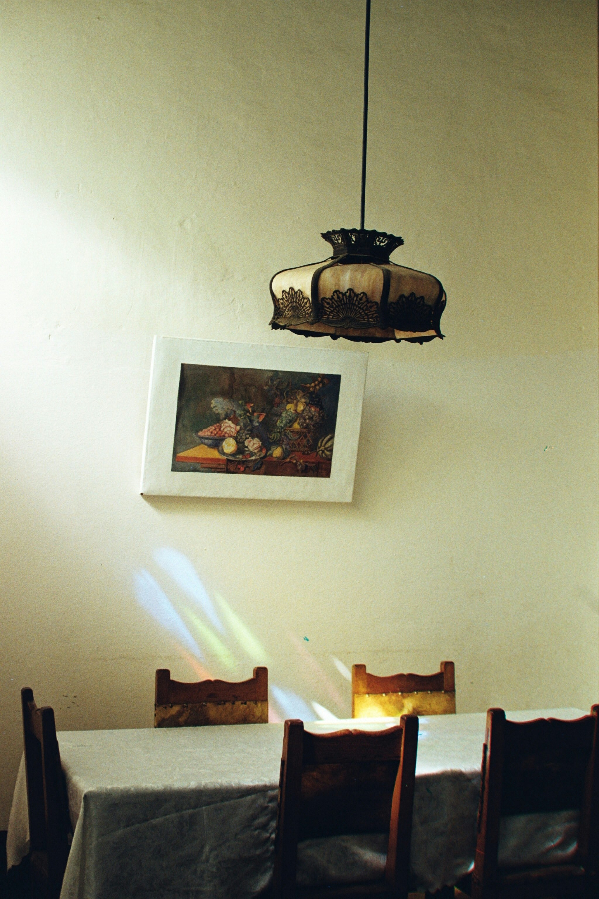 Table with chairs and a painting illuminated by sunlight.