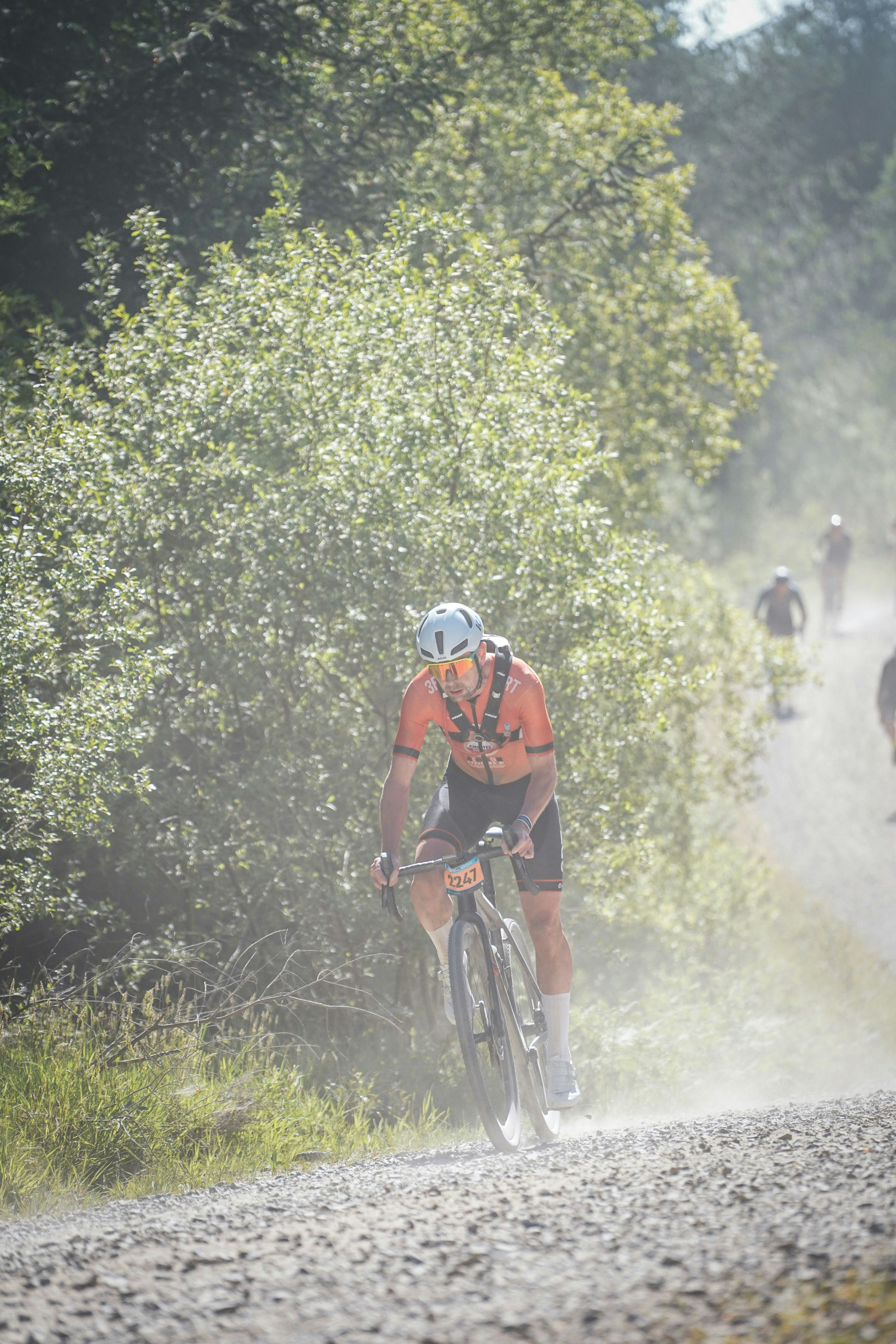 Cyclist riding on a dusty gravel road uphill.