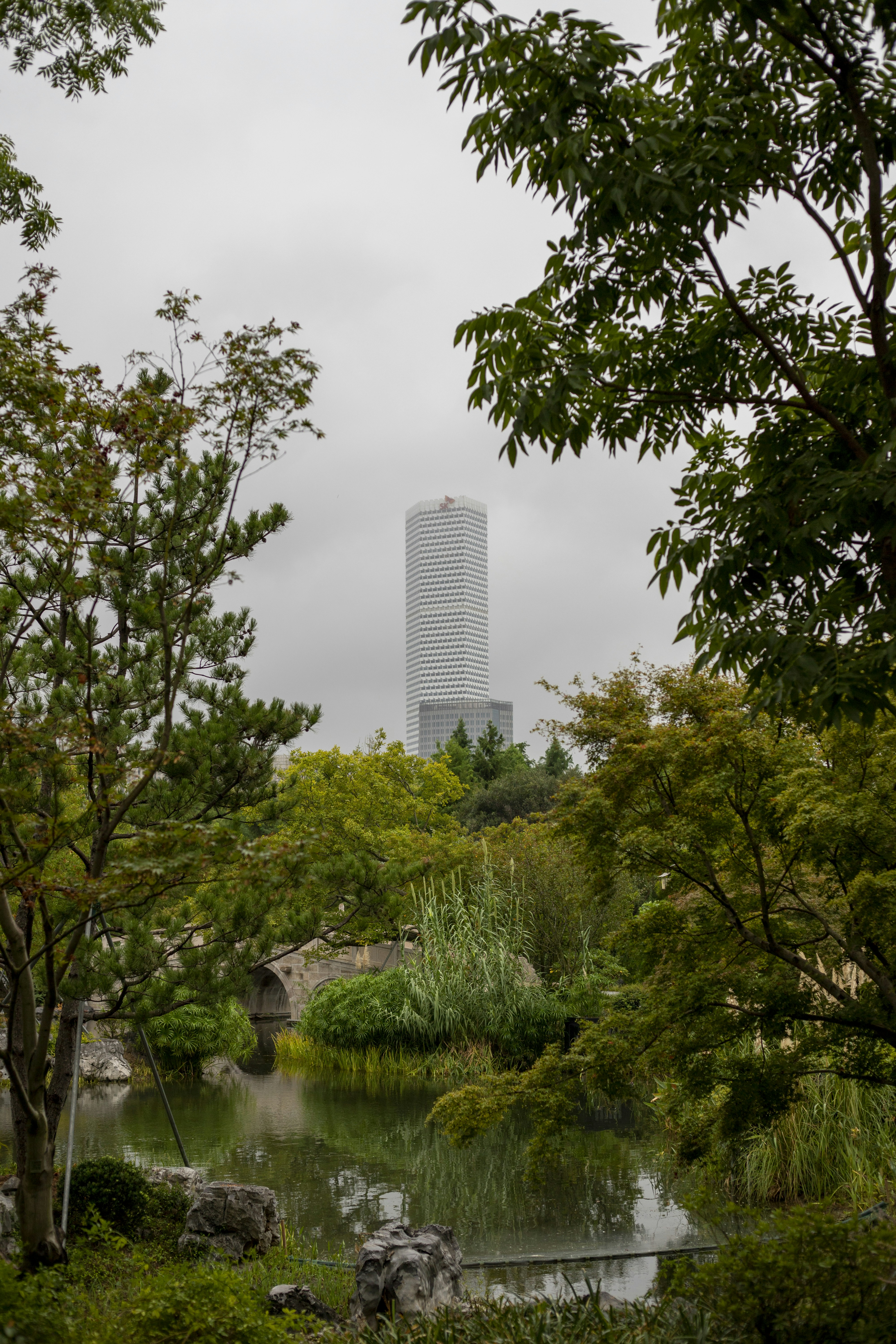 Skyscraper seen through lush green trees and garden