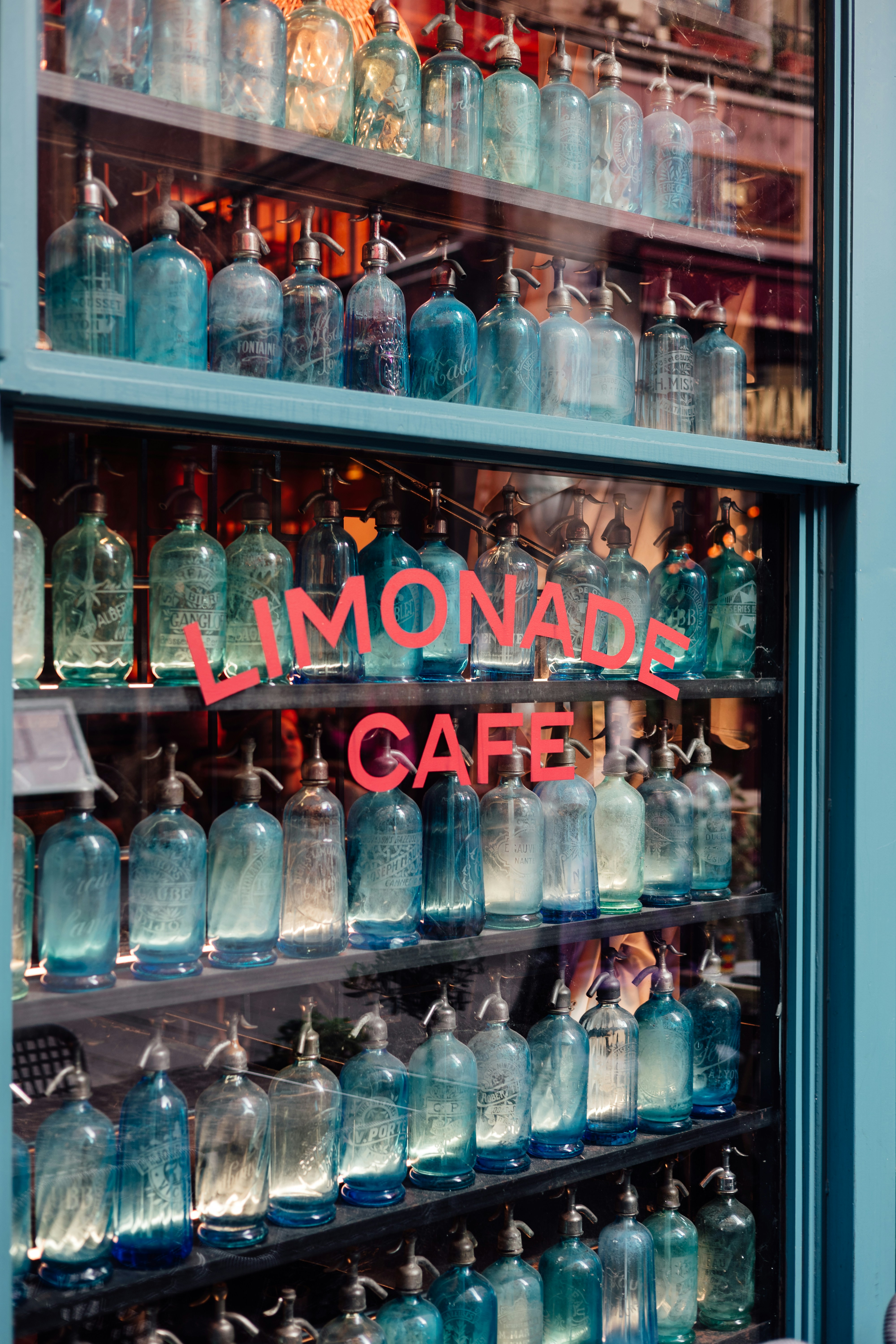Rows of vintage seltzer bottles displayed in a cafe window.