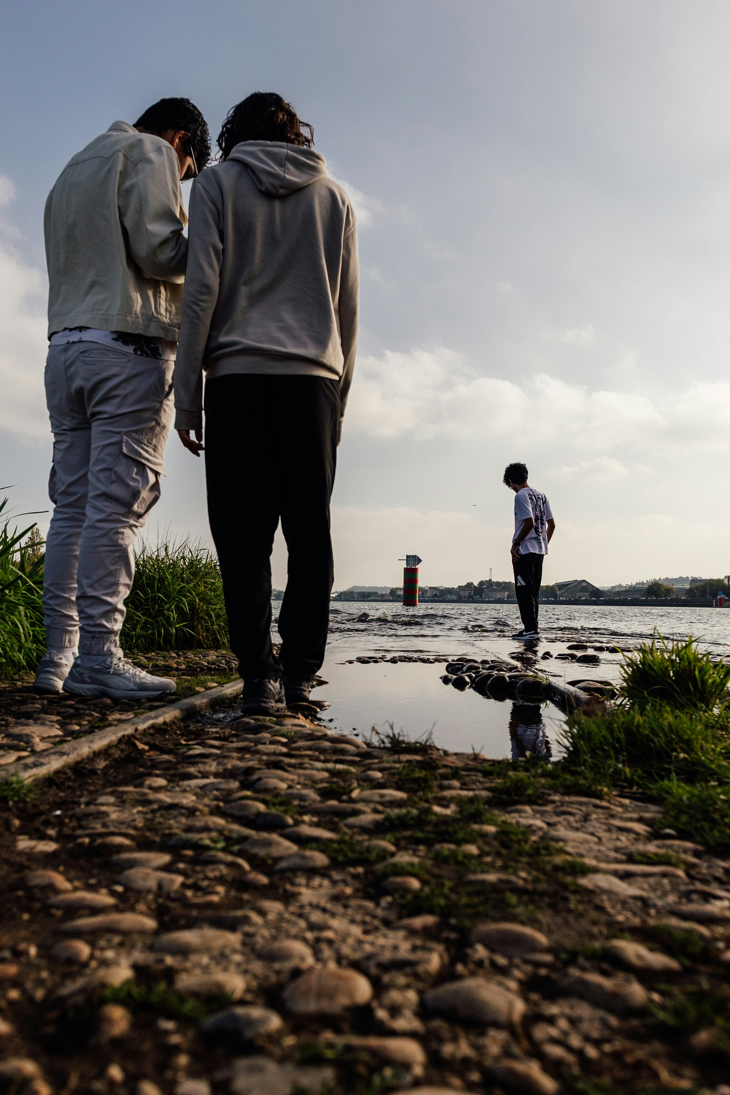 Two men look at phone by the water