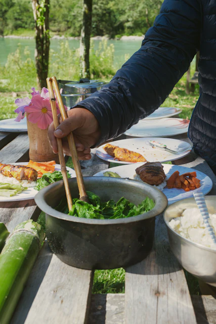 Person serving food at an outdoor picnic table.