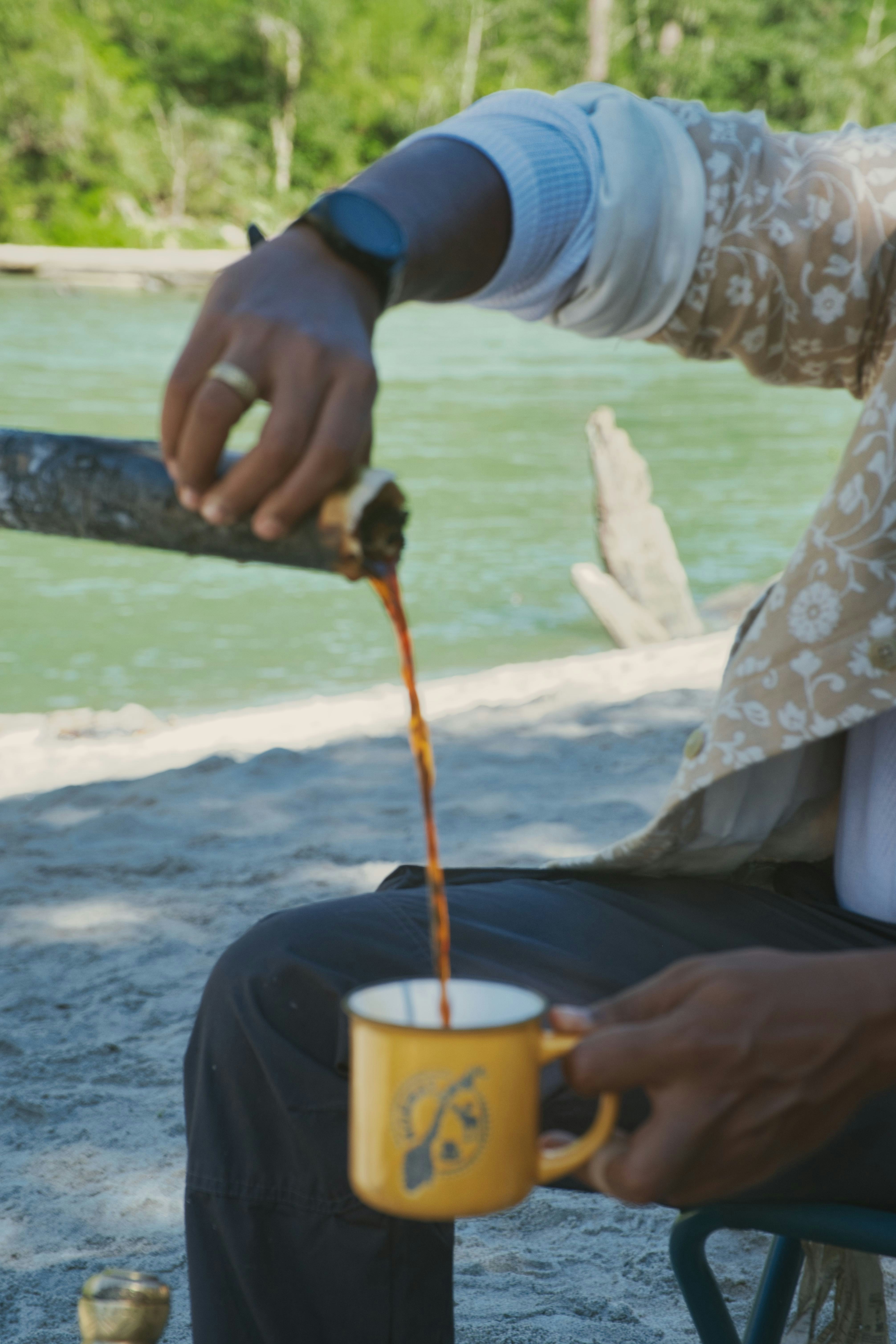 Pouring coffee into a mug by a river