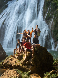 Group of friends posing on rocks near a waterfall