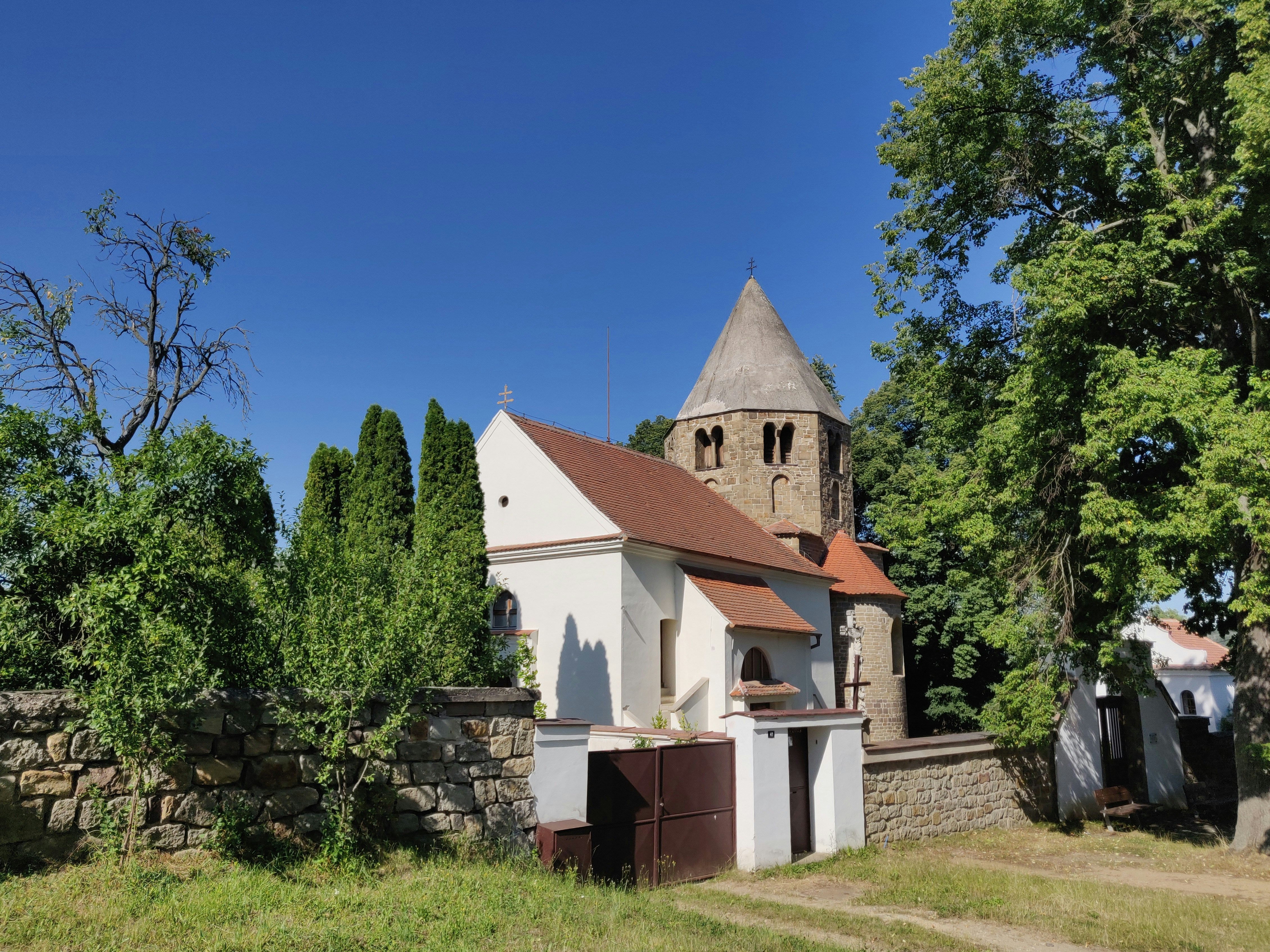 Old stone church with conical roof and trees