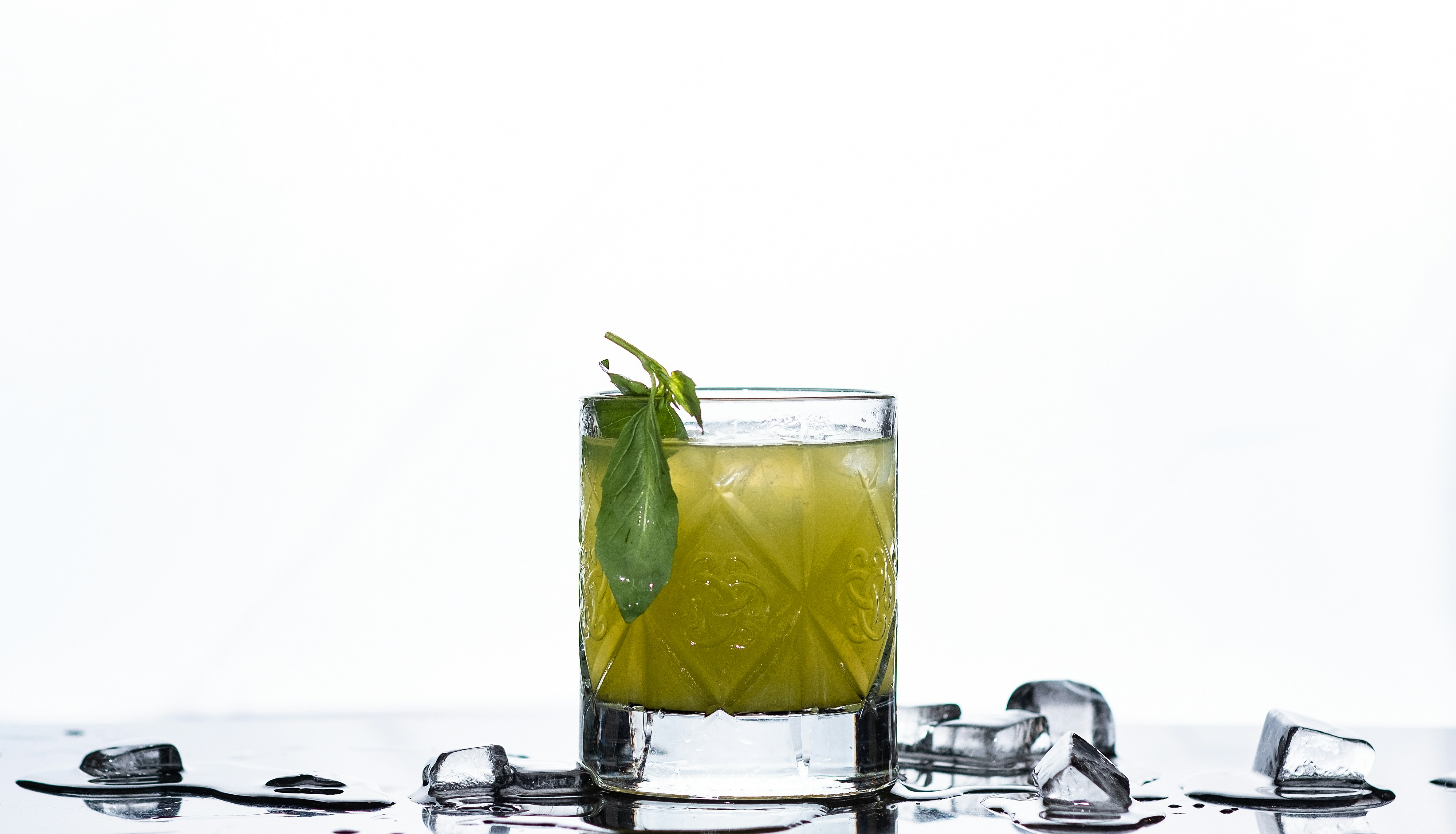 A green cocktail with ice and garnish