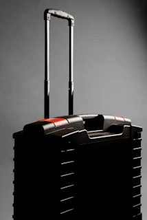 A black rolling suitcase with a telescopic handle