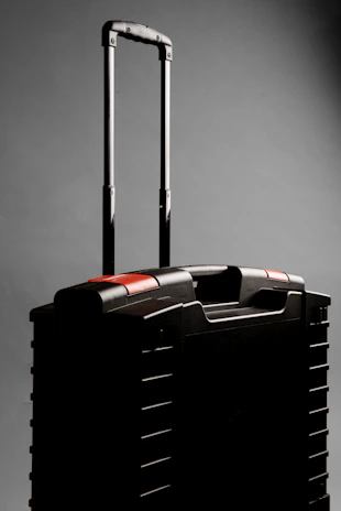 A black rolling suitcase with a telescopic handle