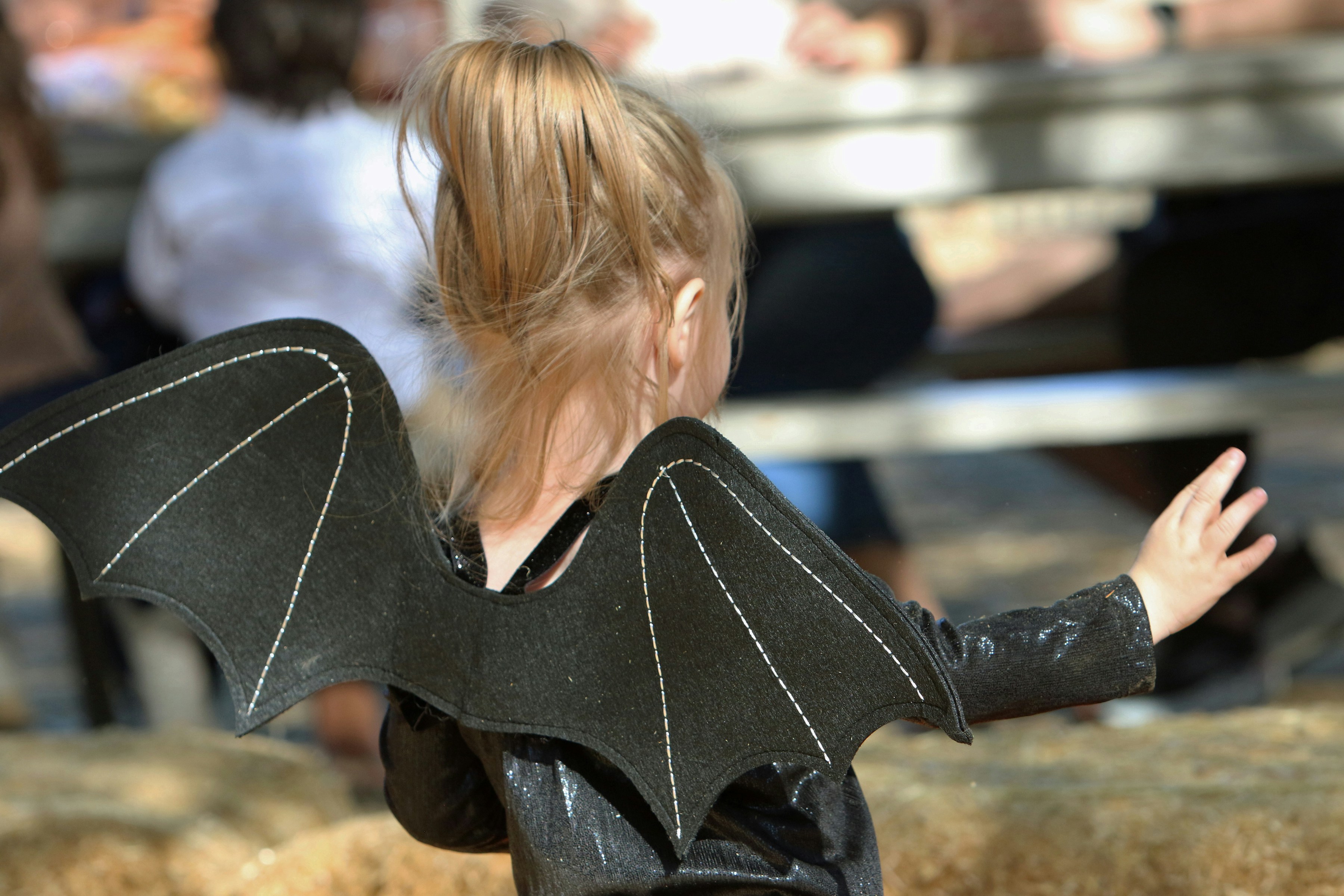 Young child wearing bat wings costume