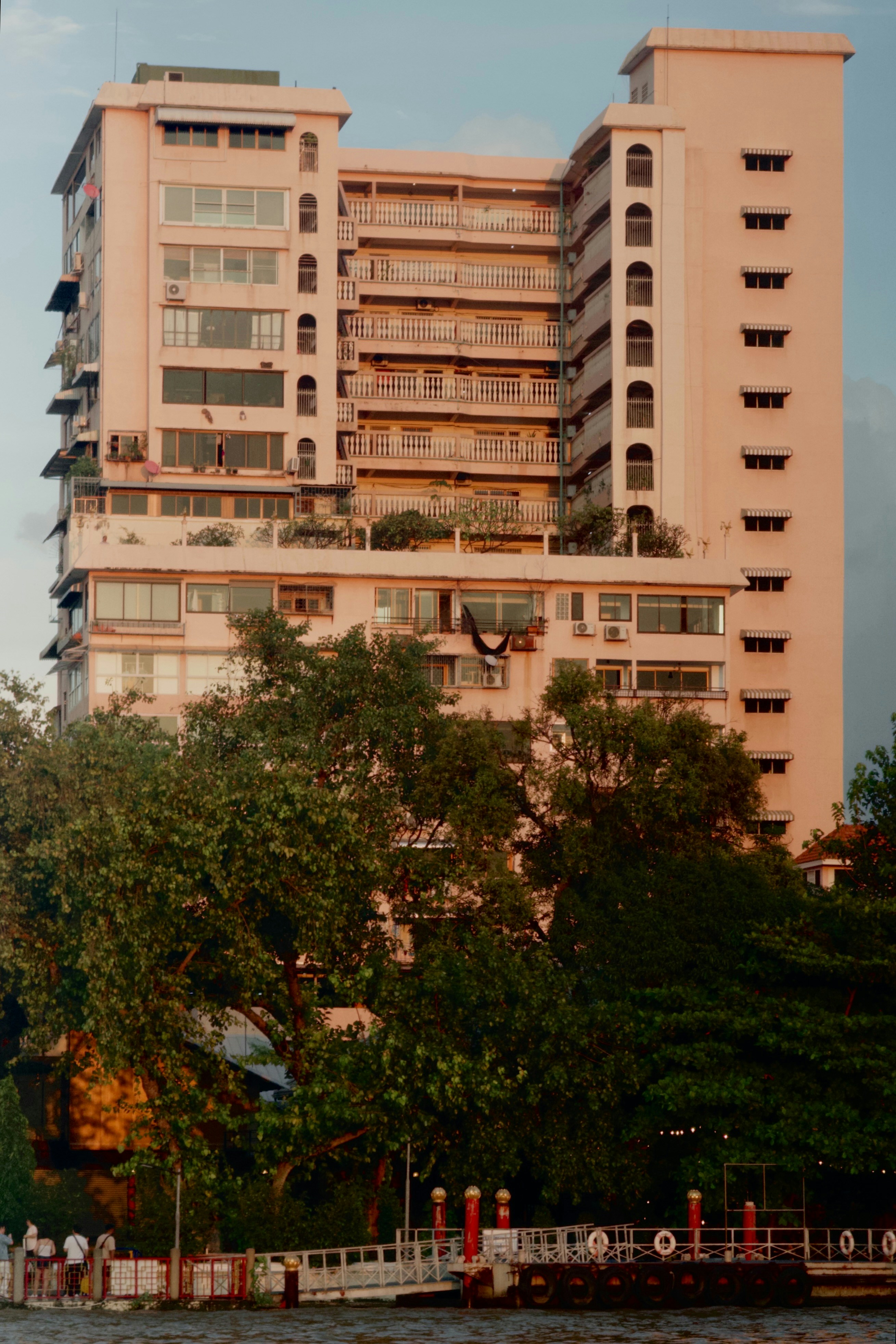 Edificio de apartamentos alto con balcones y árboles.