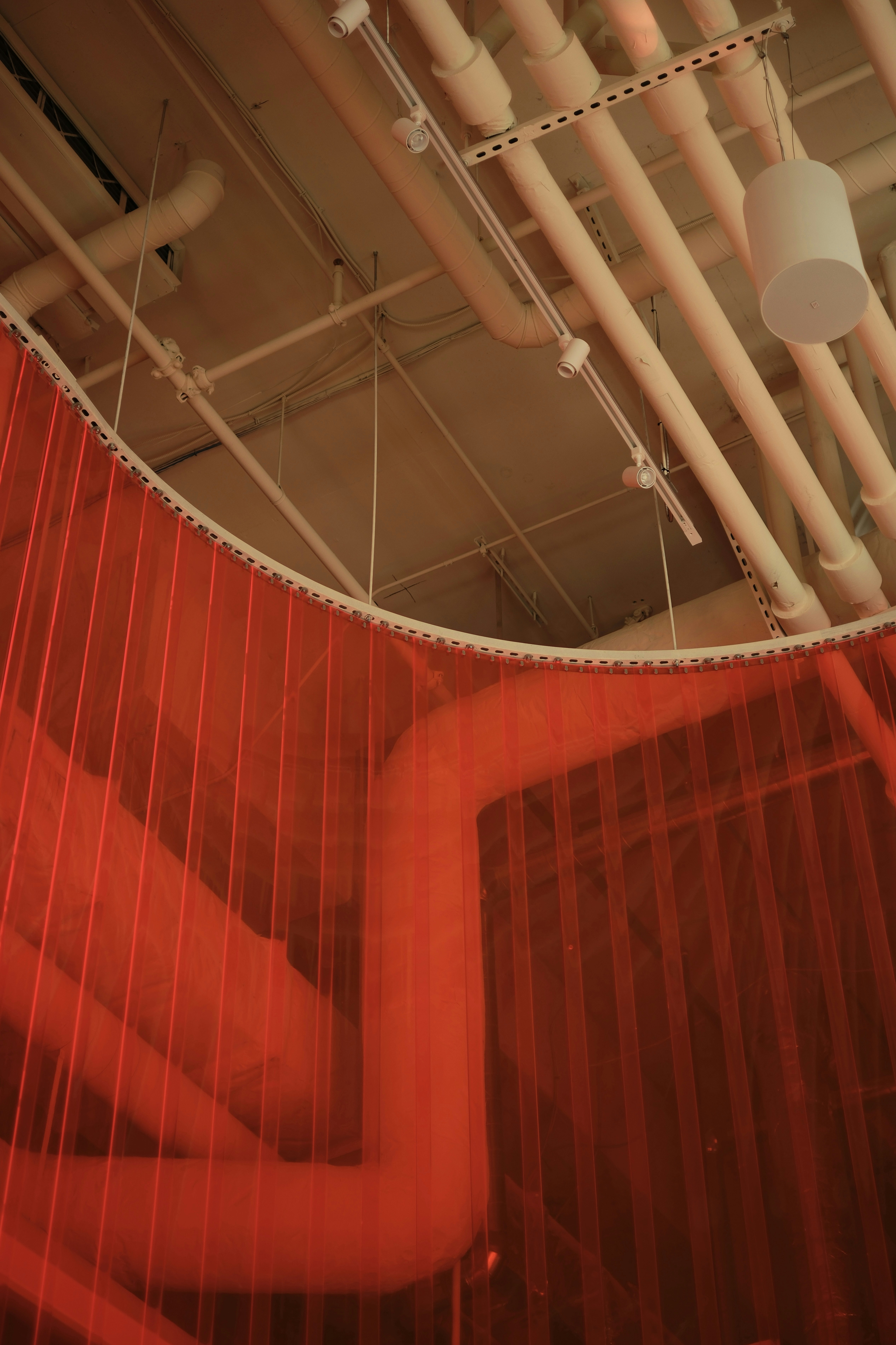 Red netting hangs in front of industrial pipes