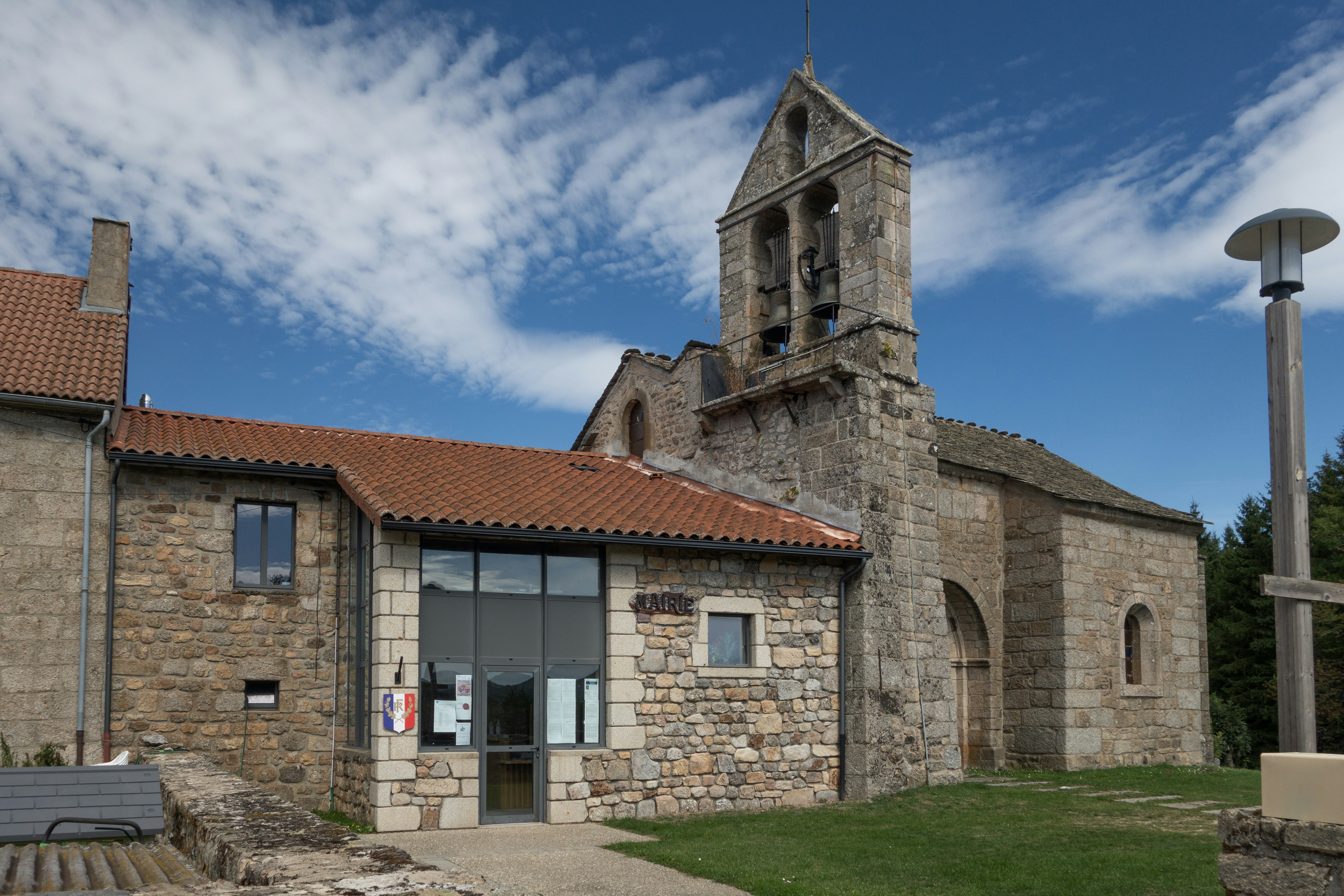 Stone church building with bell tower and modern addition.