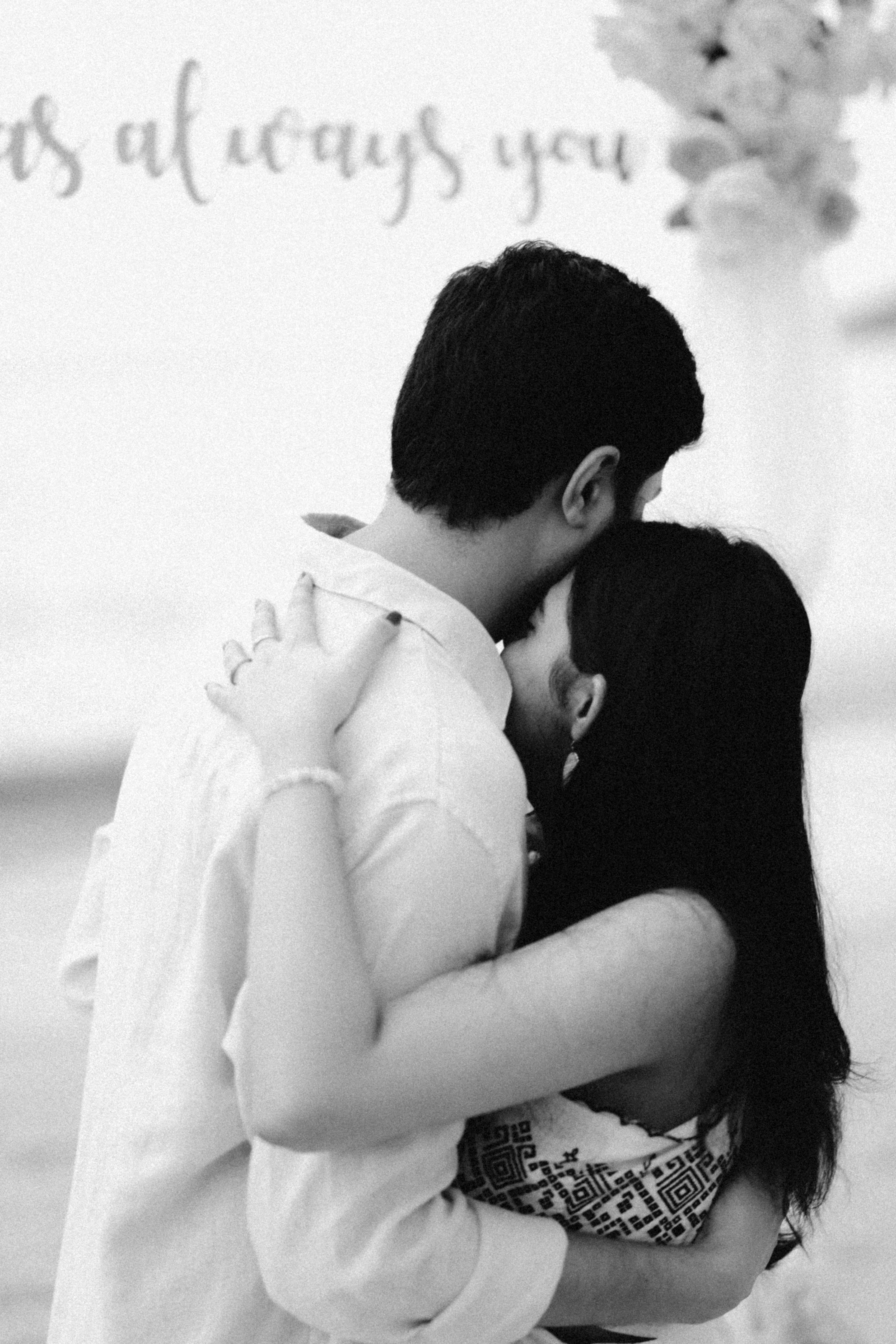 Couple embracing on a beach with floral decorations.