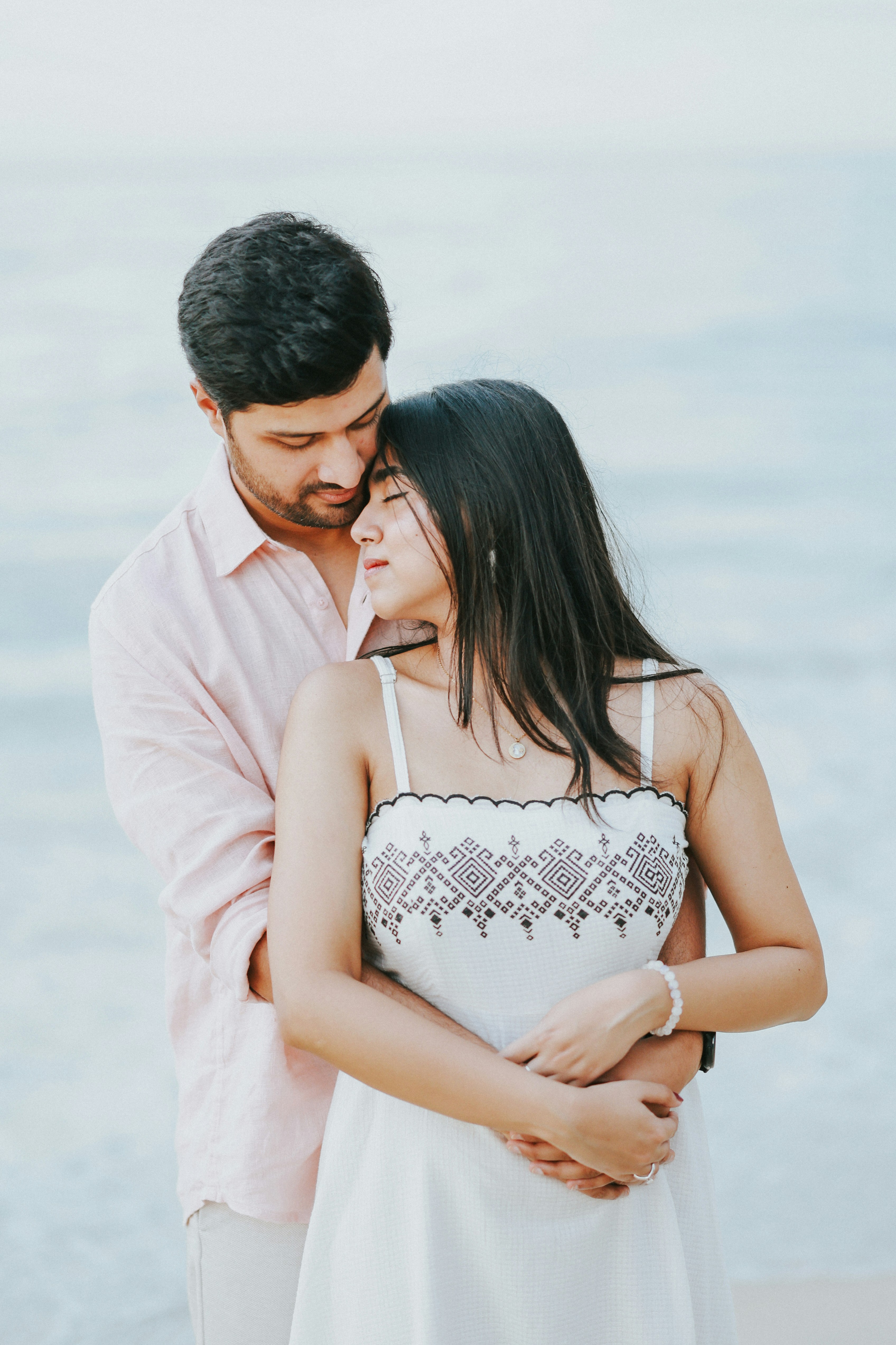 Couple embracing on a beach with ocean background