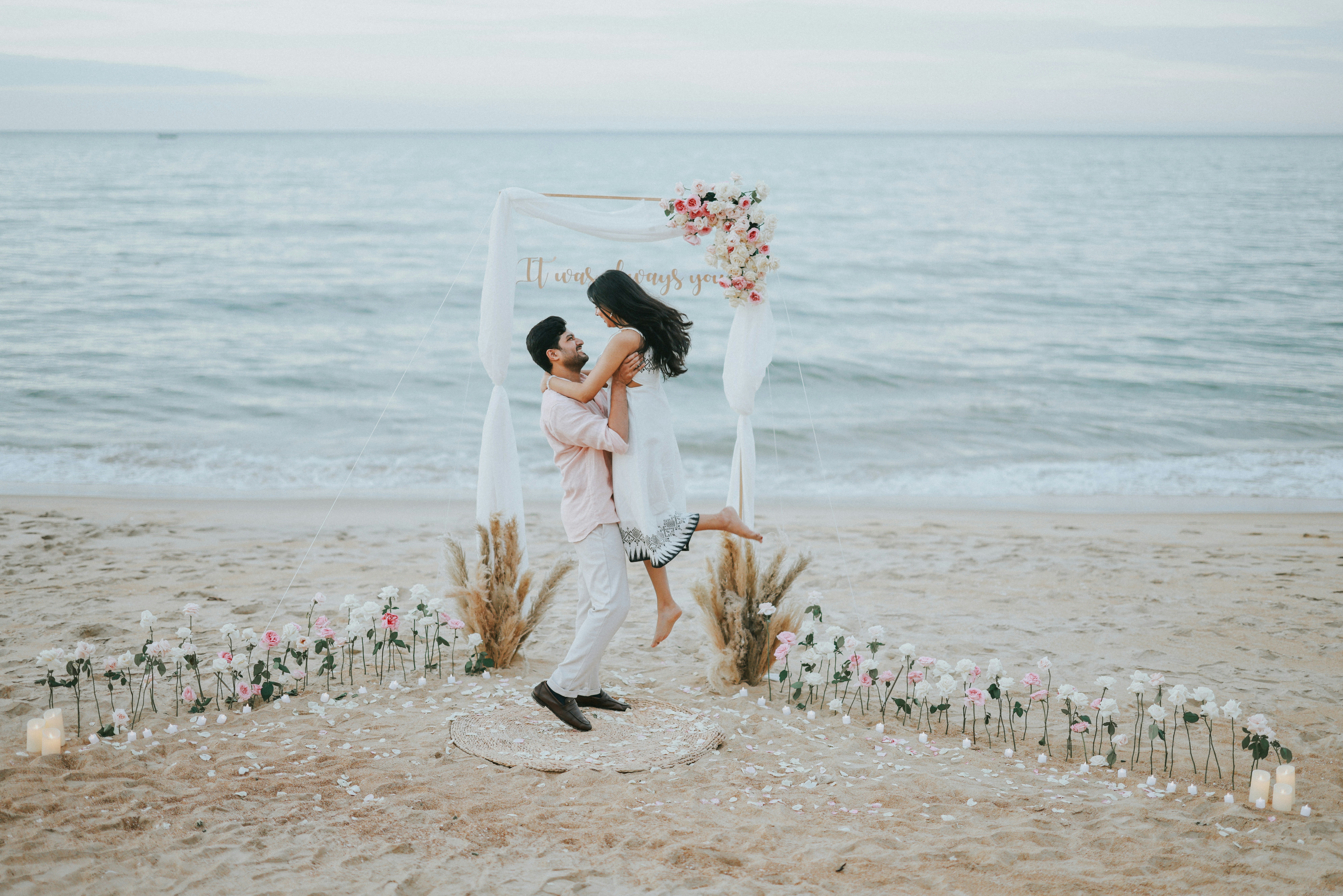 Couple celebrating on beach with floral arch
