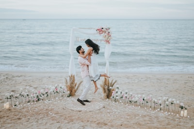 Couple celebrating on a beach with floral arch