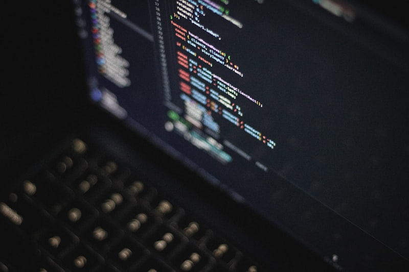 Close-up of a laptop screen displaying colorful syntax-highlighted code in a dark editor at night