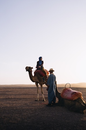 Woman riding camel with guide in desert