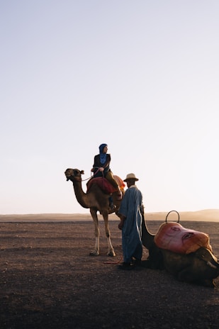Woman riding camel with guide in desert
