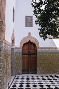 Ornate wooden door with patterned tiles and checkered floor.