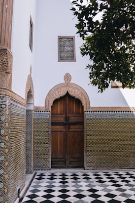 Ornate wooden door with patterned tiles and checkered floor.