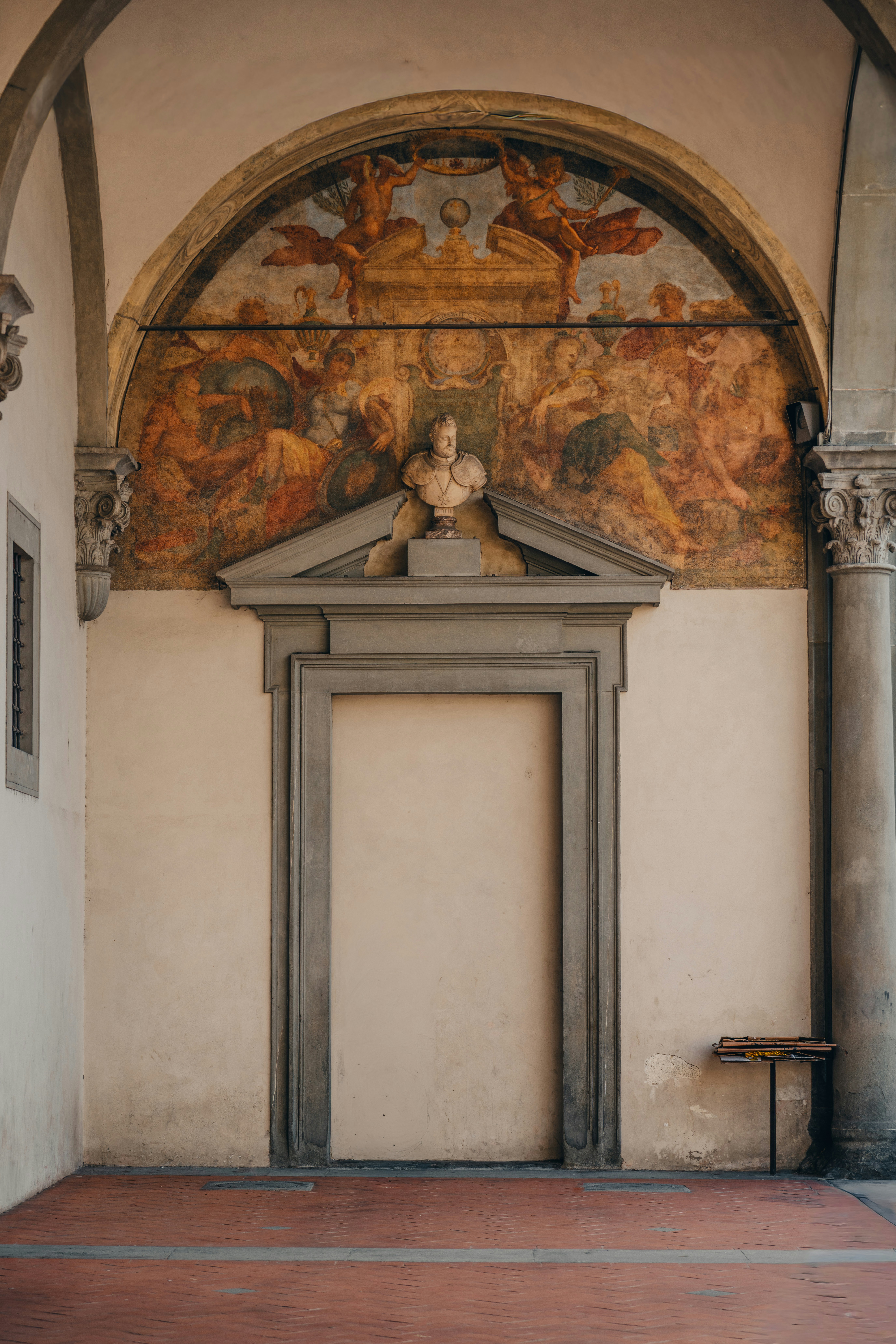 Arcade avec fresque murale et buste au-dessus de la porte