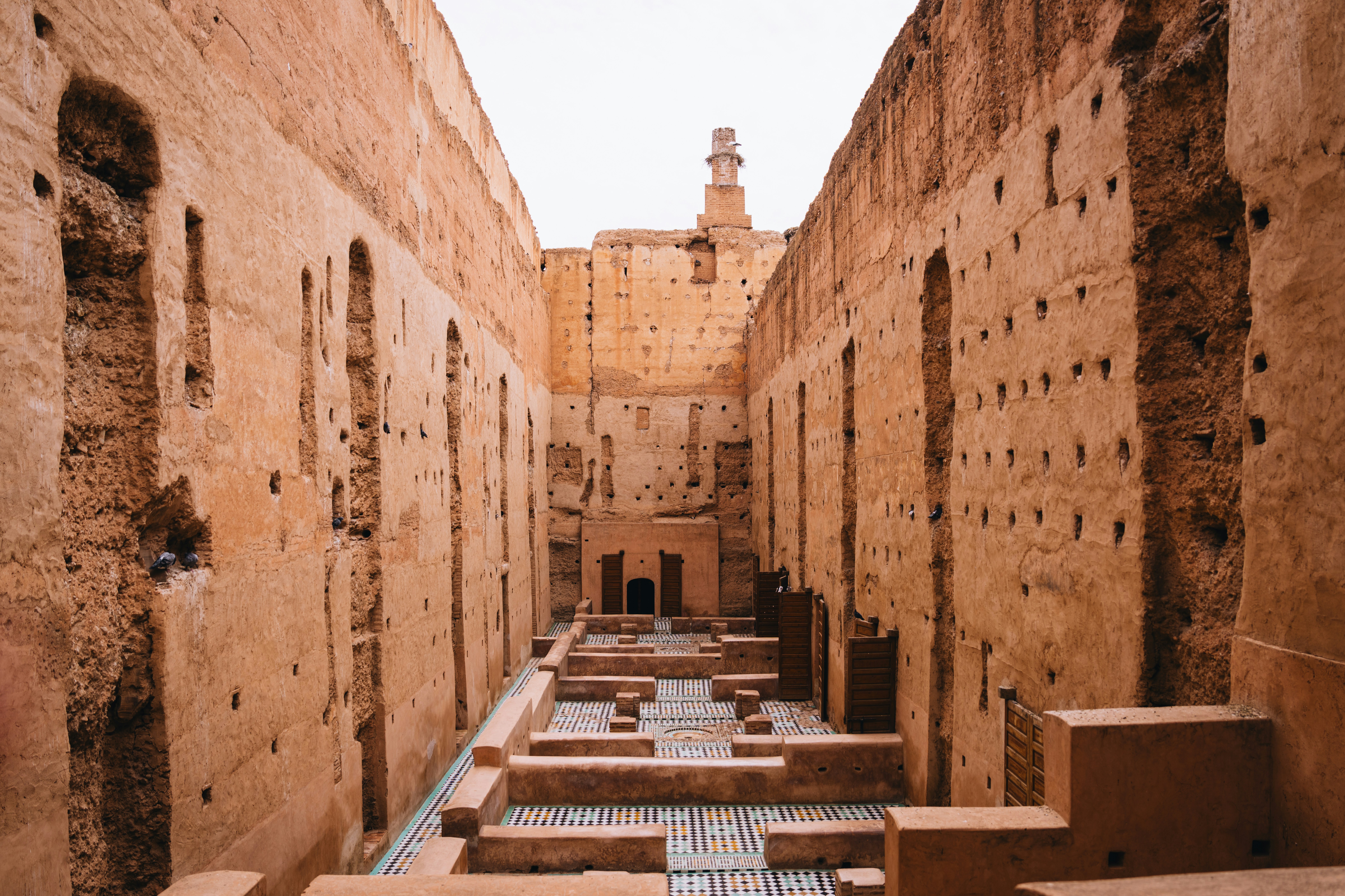 Ancient courtyard with crumbling walls and a distant tower.