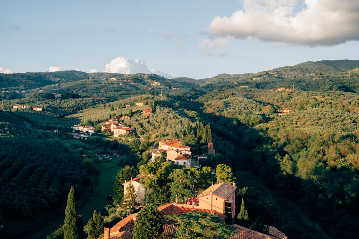 Colline toscane al tramonto con borgo e vigneti dorati della vendemmia di settembre