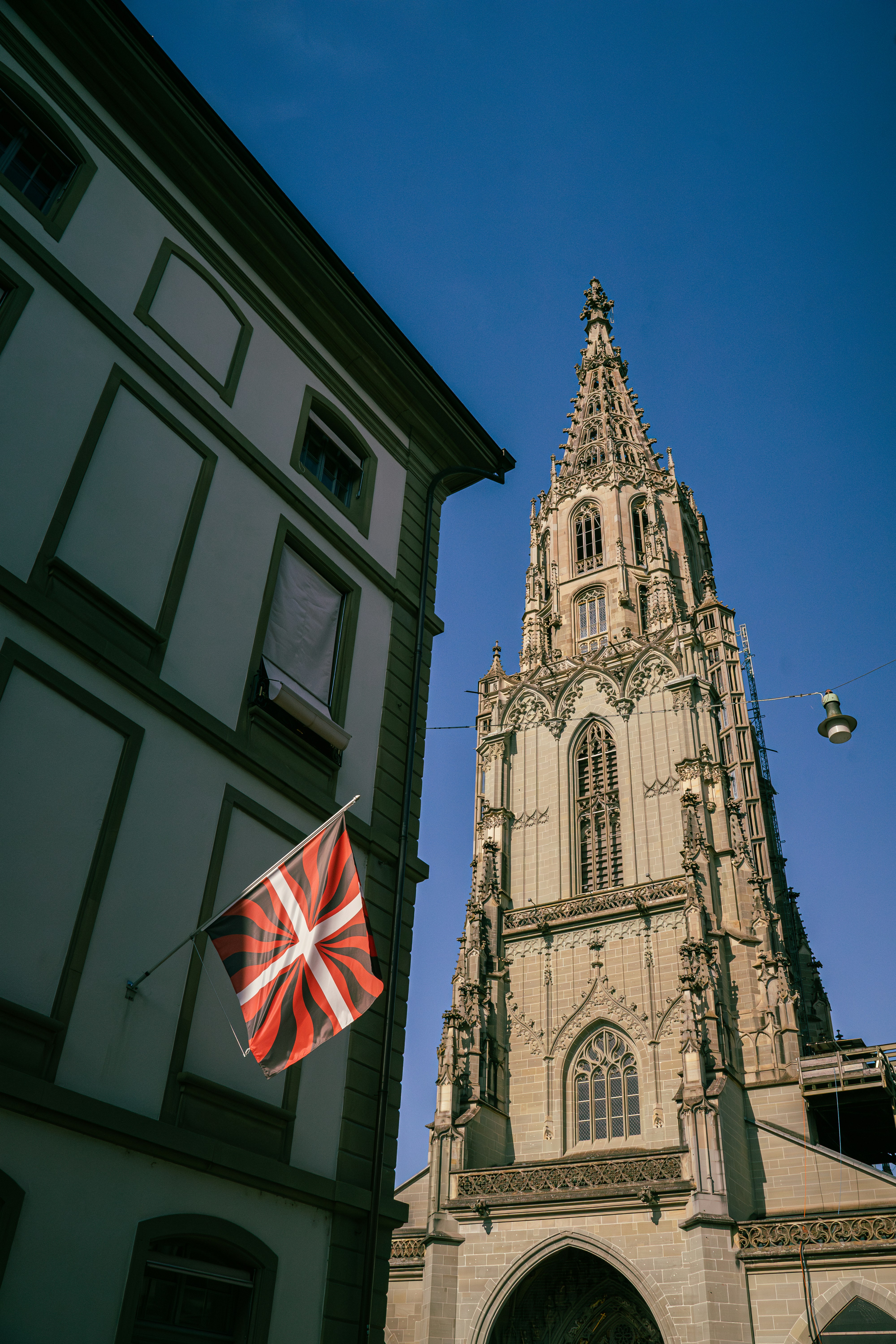 Gothic cathedral tower with a flag against blue sky