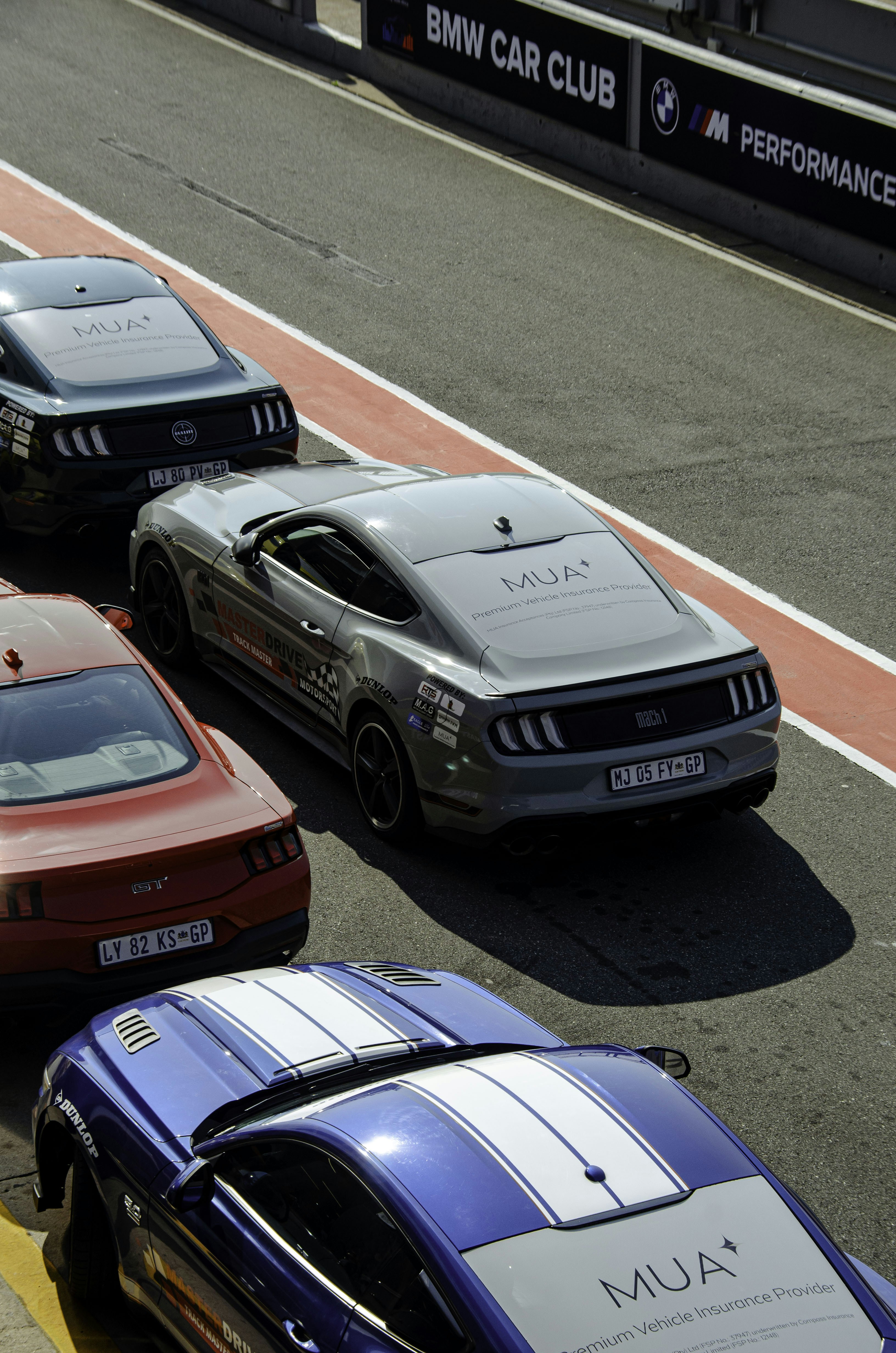 Several ford mustangs lined up on a track.