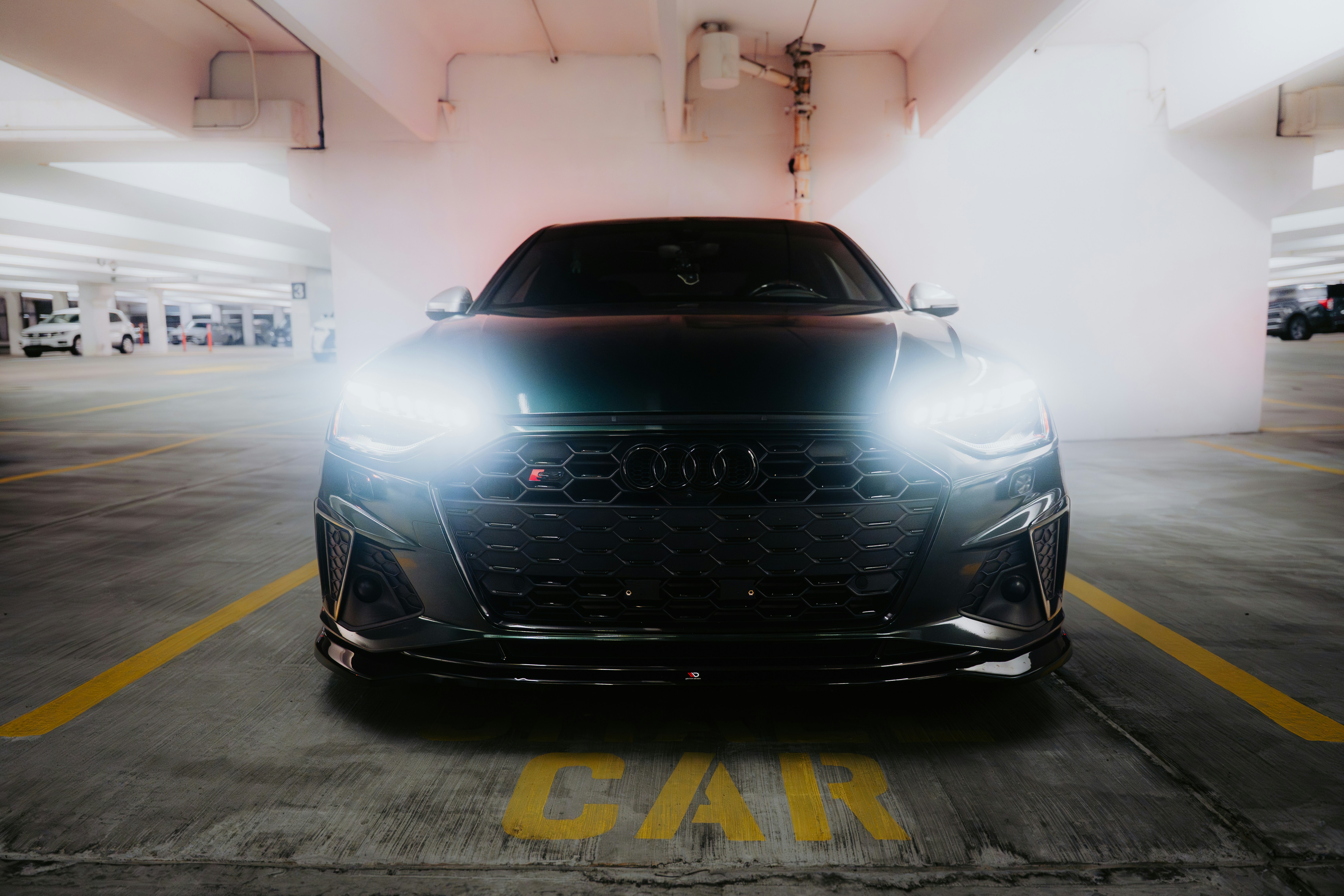 Black luxury car parked in a dimly lit garage.