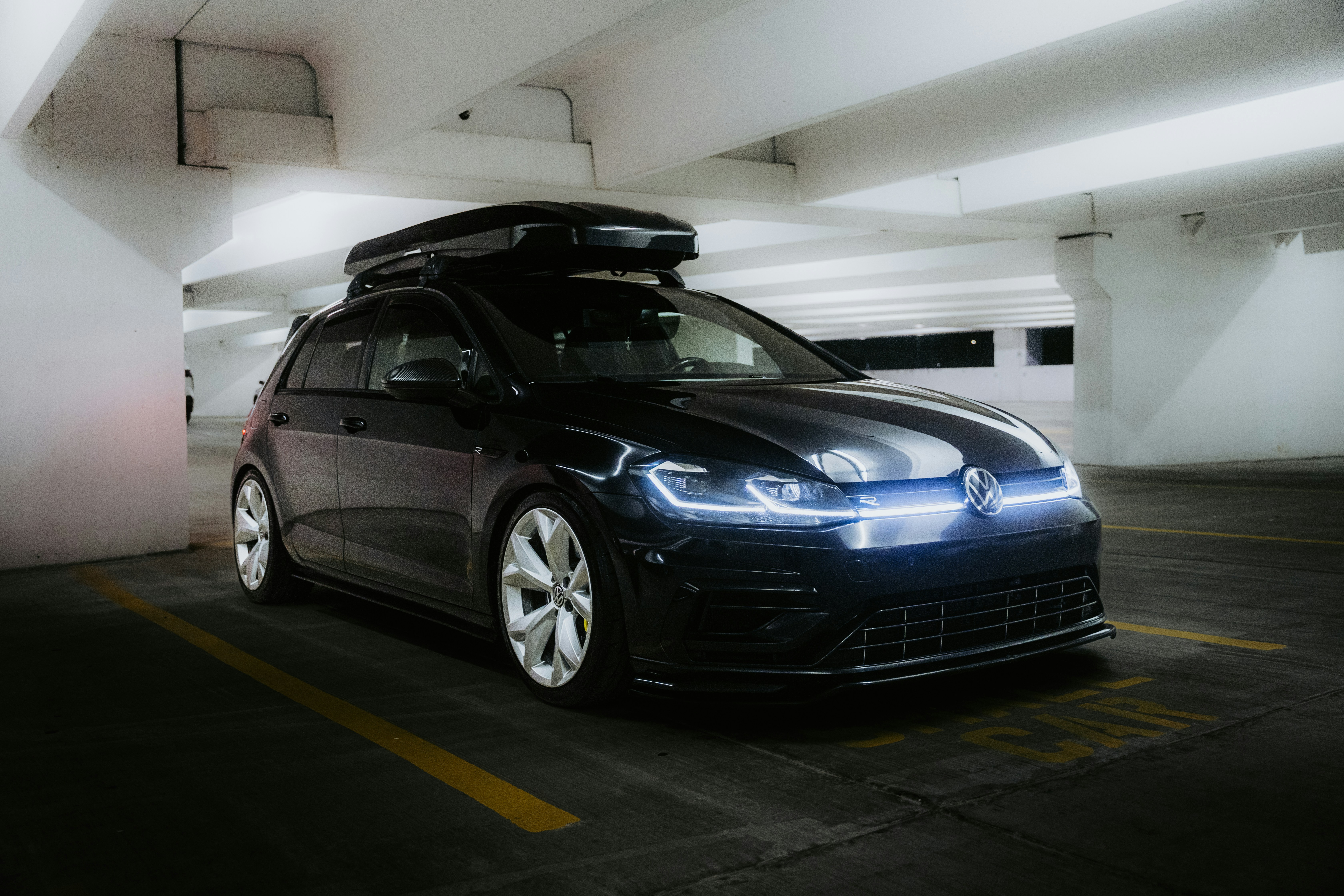 Black volkswagen golf with roof box in parking garage