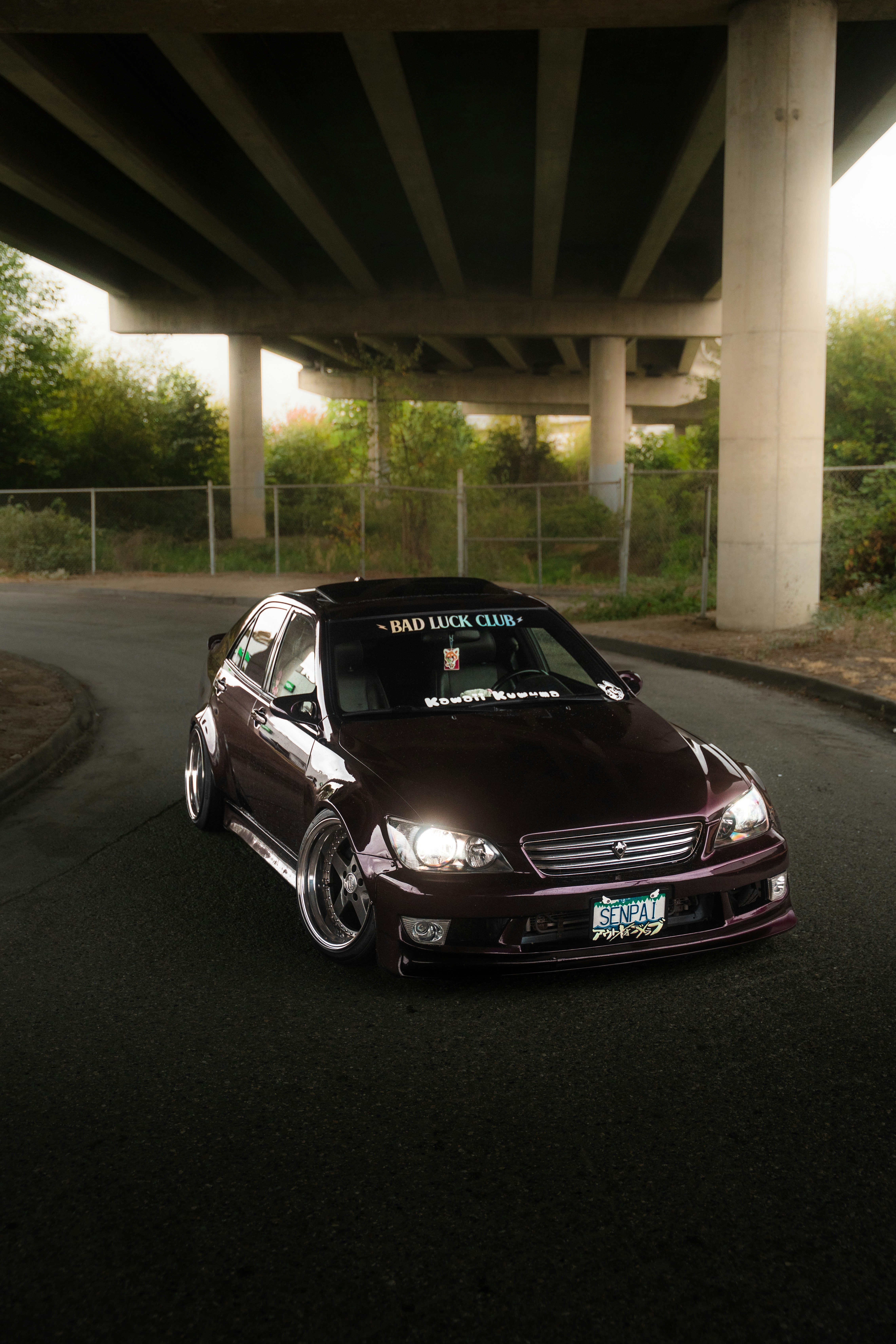 Modified purple sedan parked under an overpass