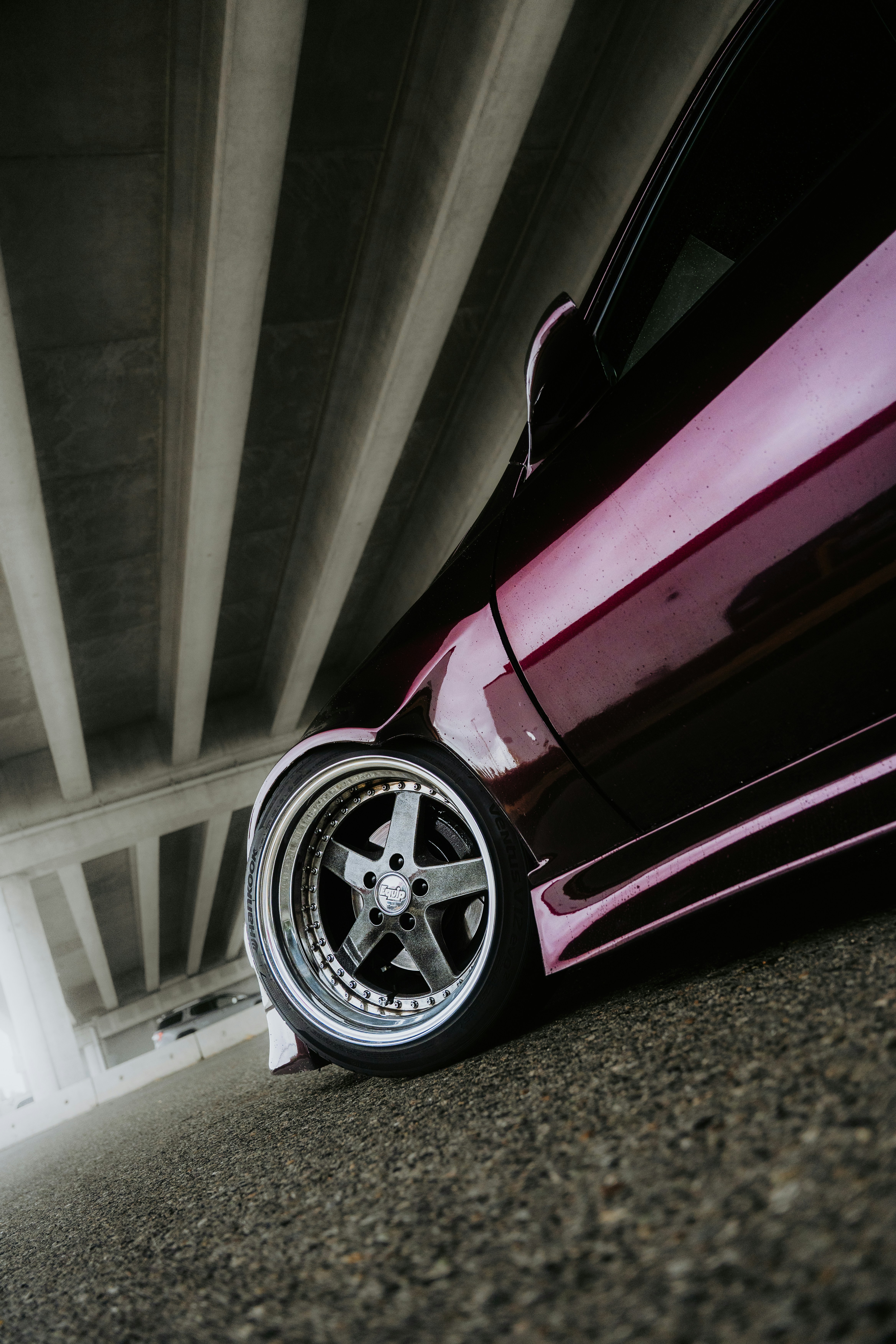 Close-up of a custom car wheel under a bridge