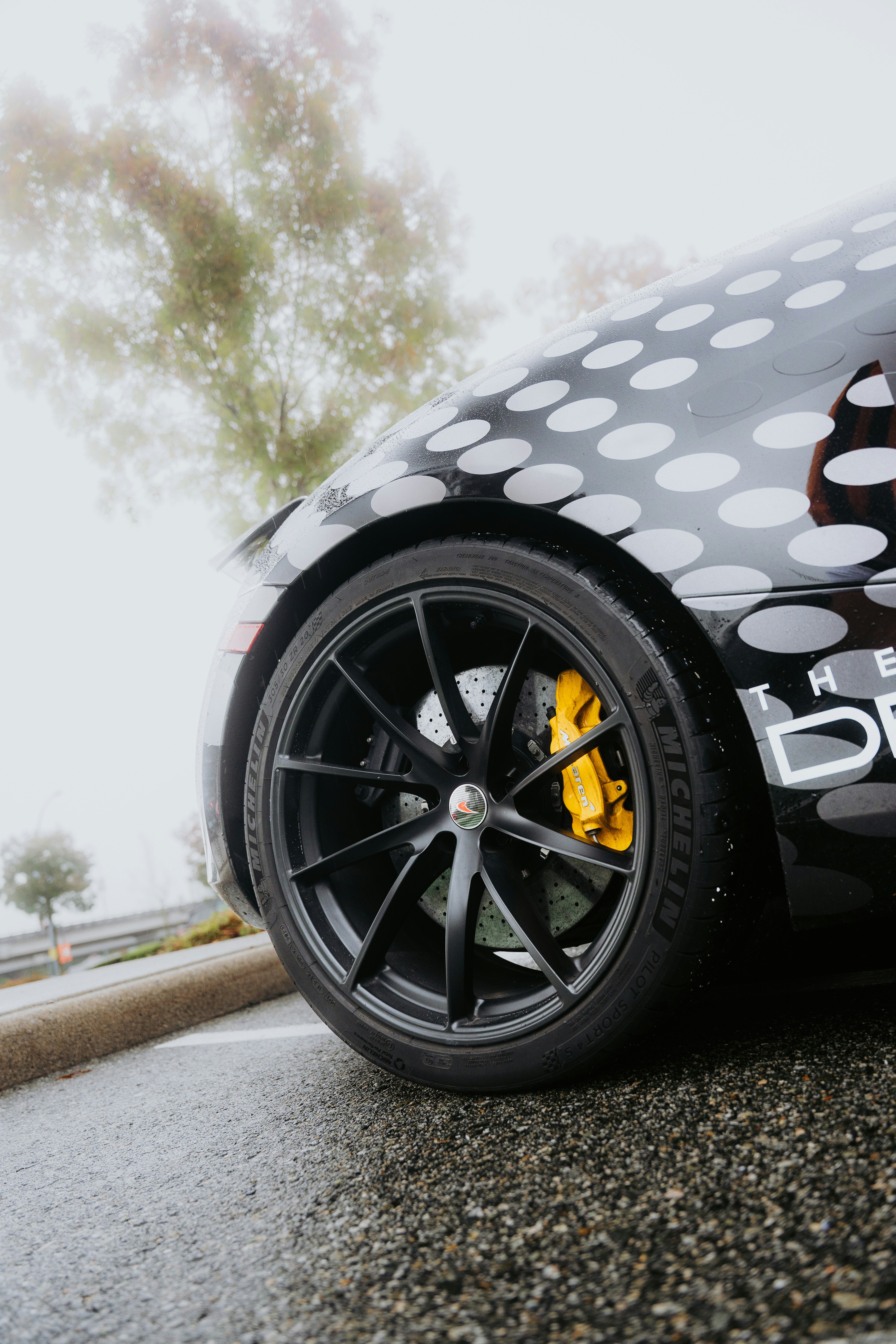 Close-up of a black car wheel with yellow brake caliper.