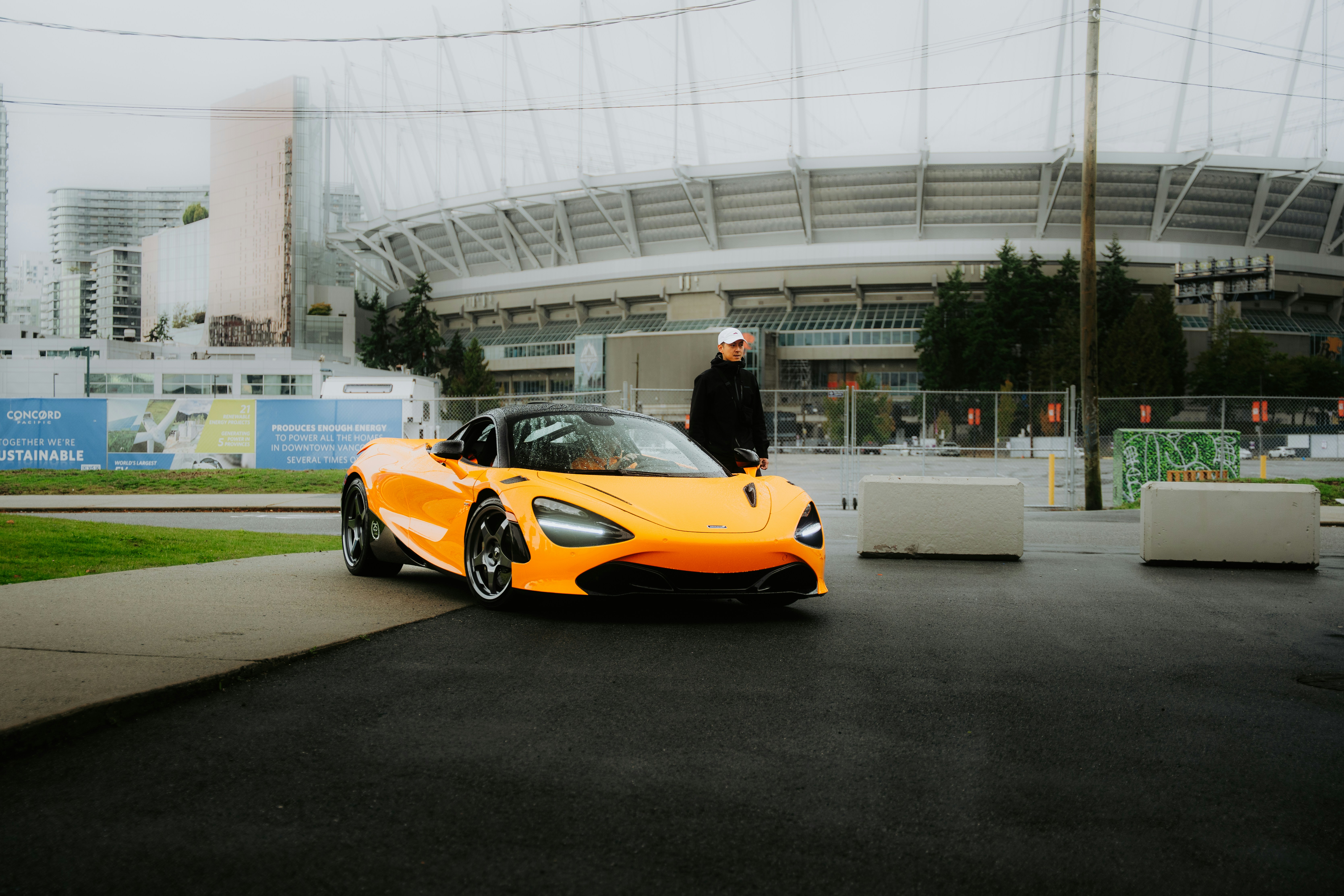 Man standing next to an orange sports car