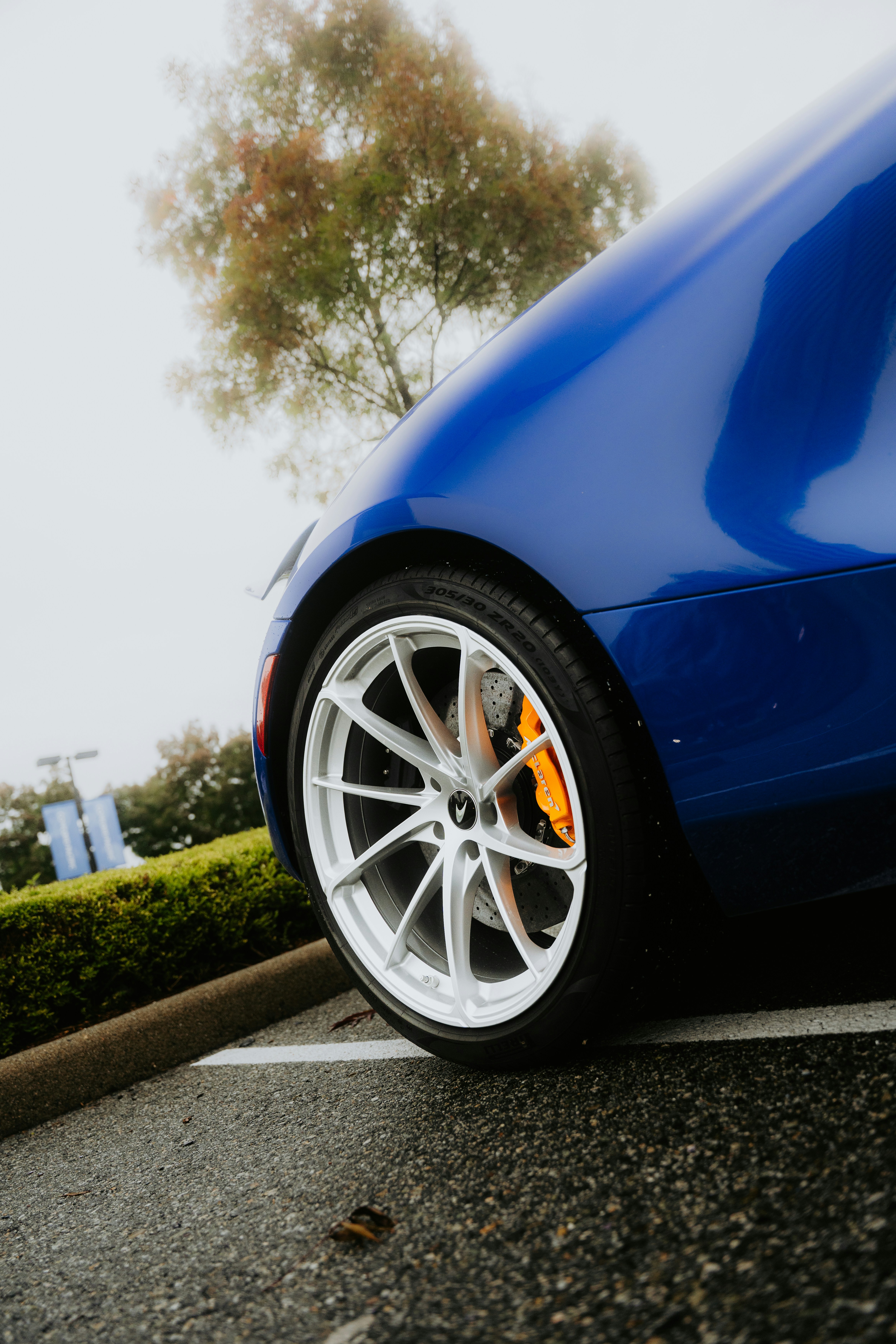 Close-up of a blue car wheel with orange brake calipers.