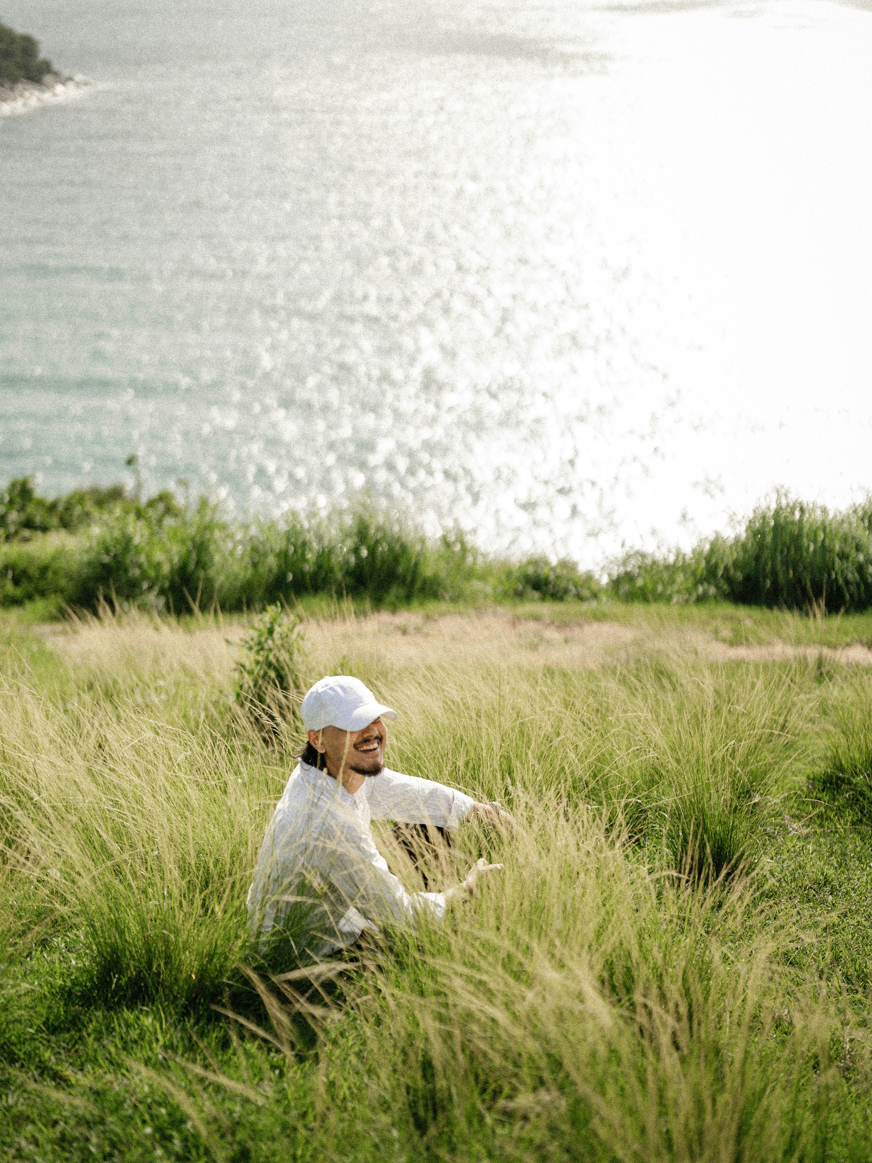 Person sitting in tall grass overlooking ocean