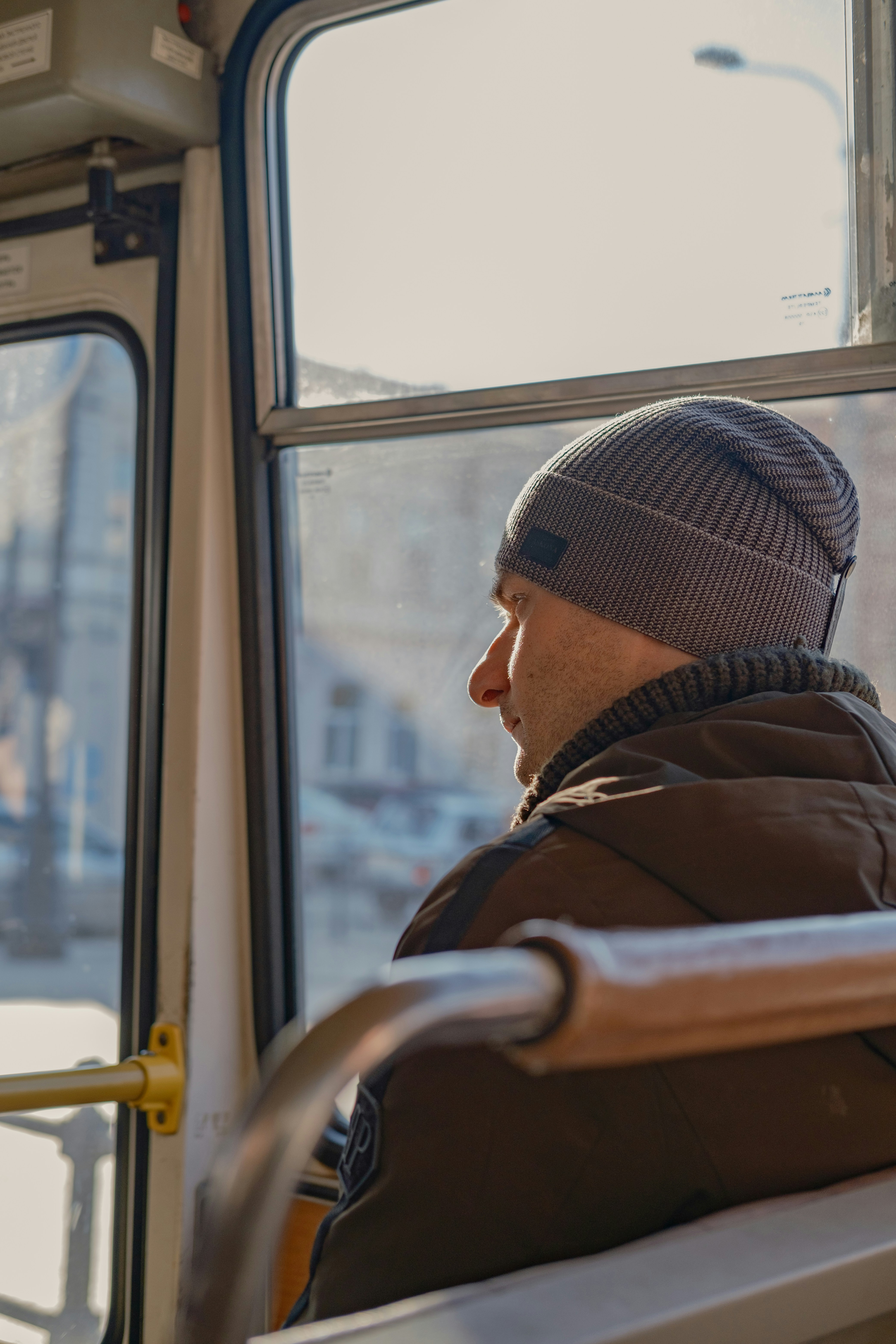 Man wearing a beanie looking out bus window