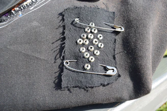 Black fabric patch with safety pins and studs