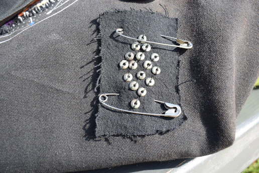 Black fabric patch with safety pins and studs