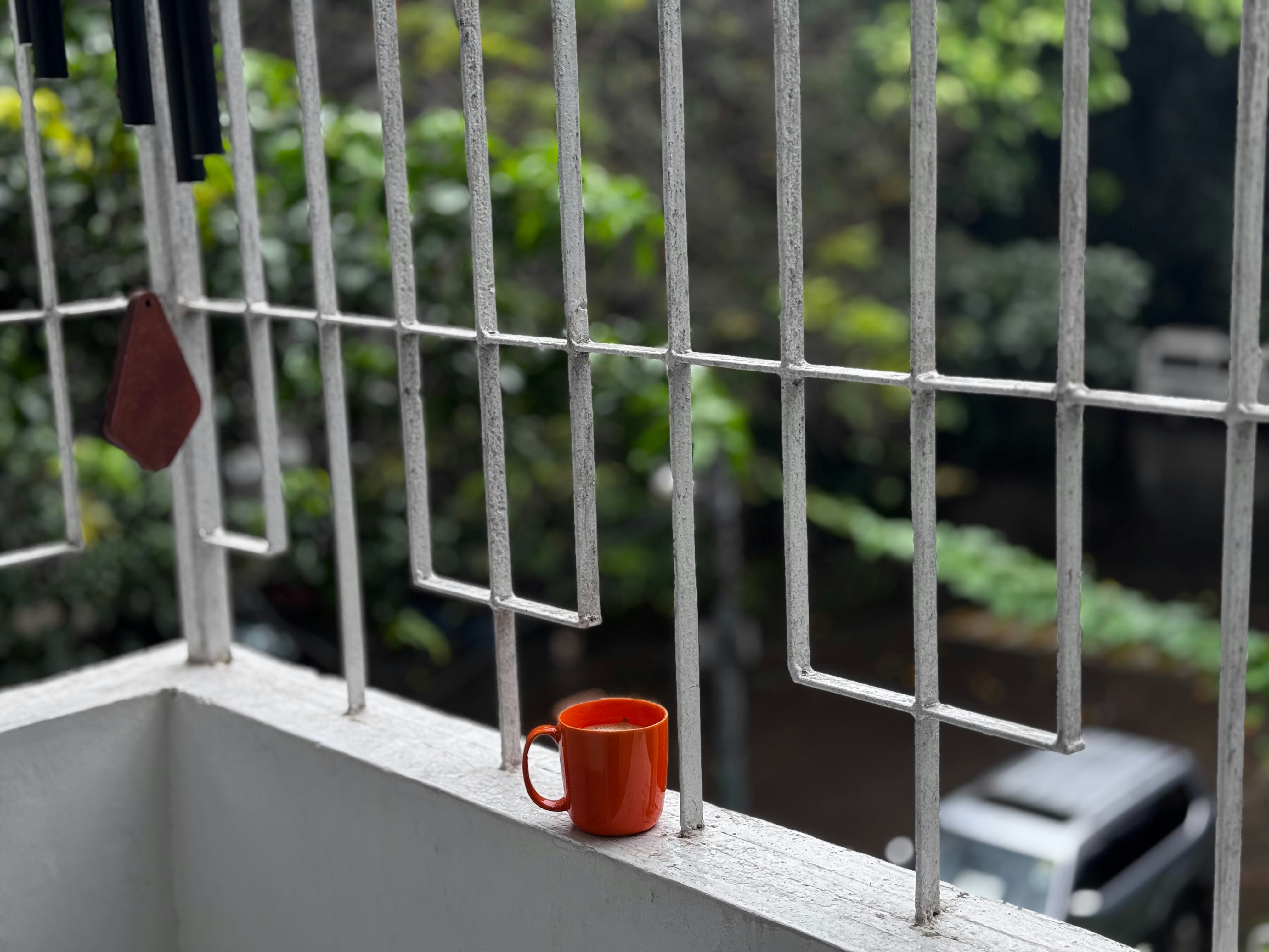 Orange mug on a balcony railing with greenery.