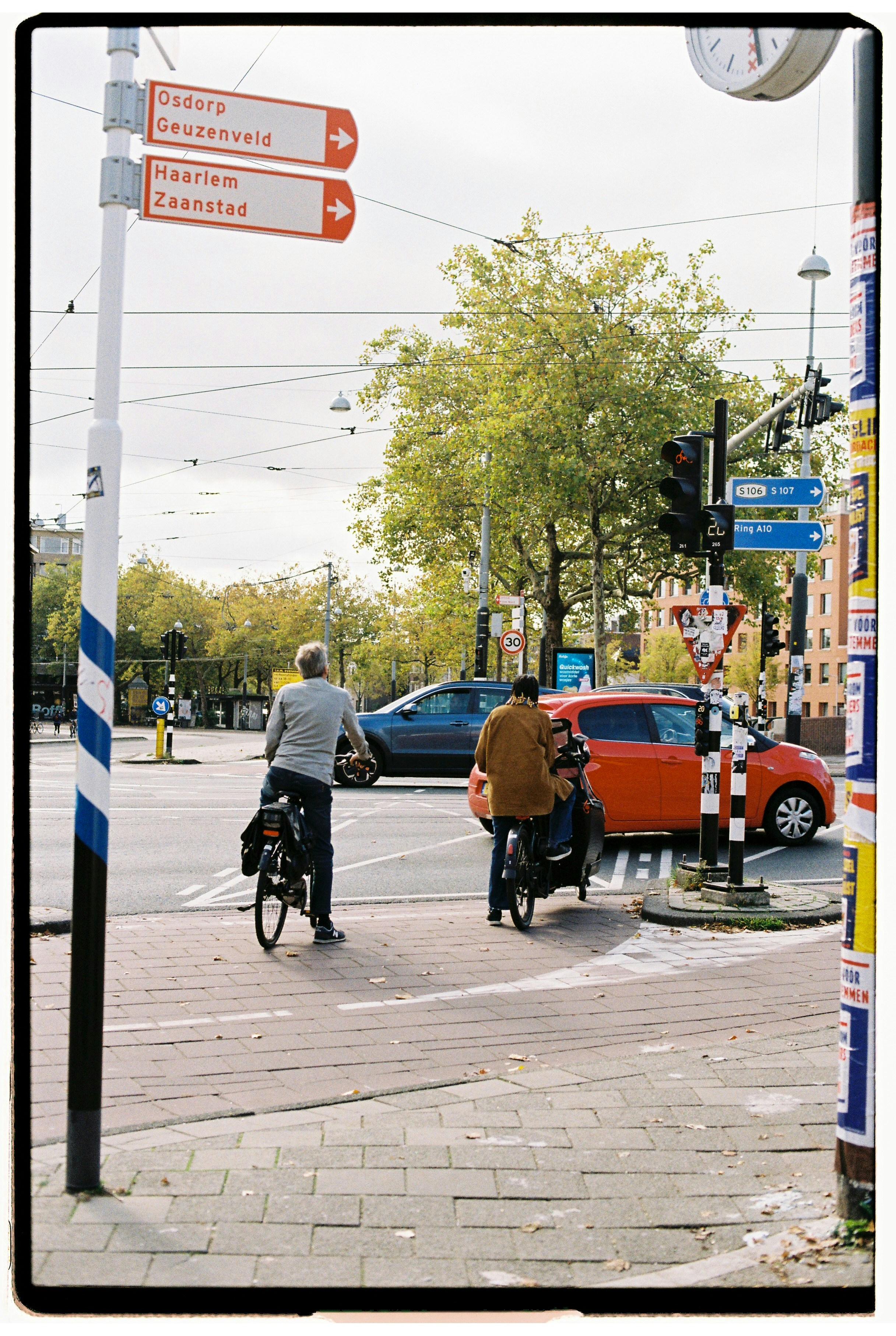 Cyclists at a city intersection with street signs.