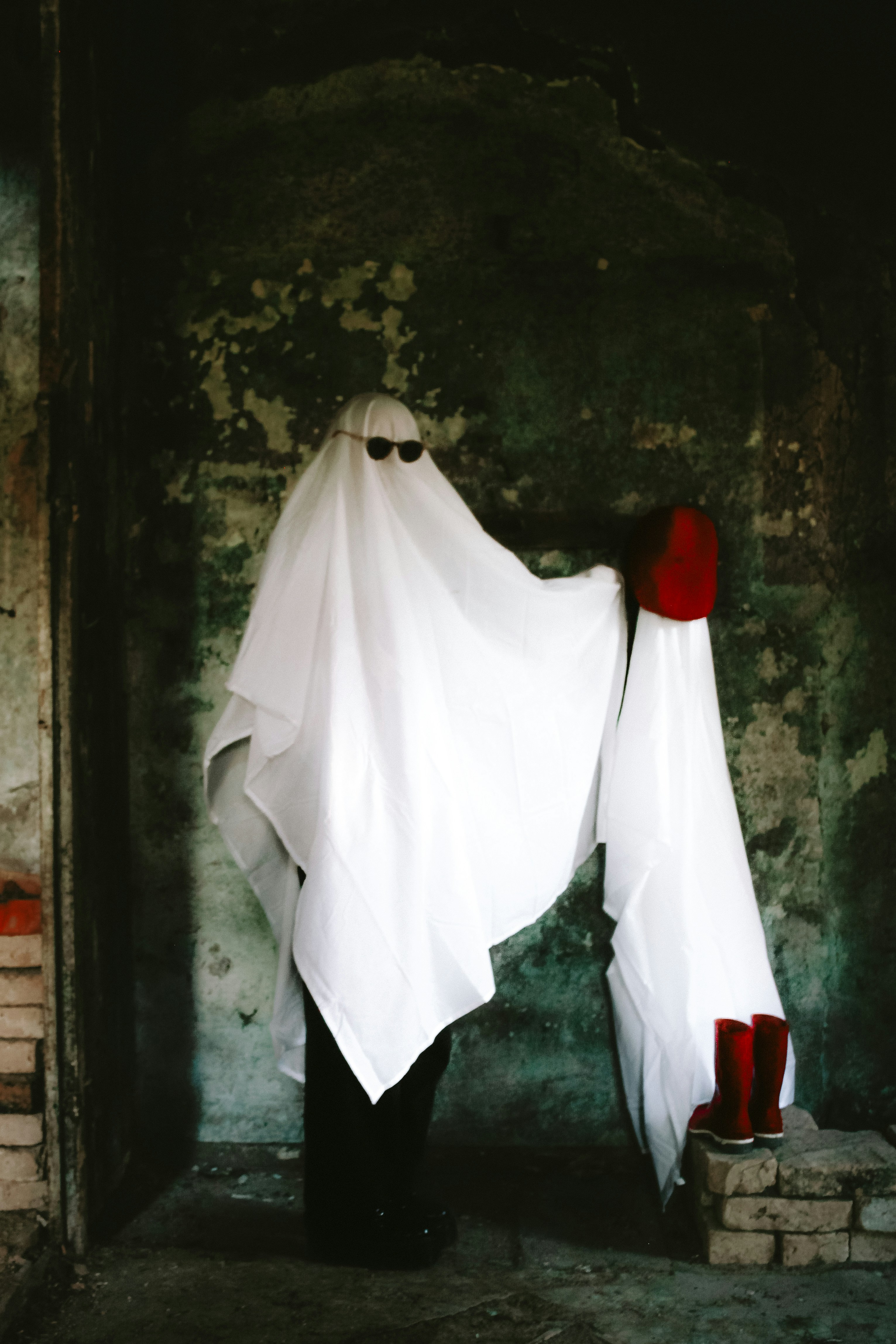 Person in ghost costume wearing sunglasses and boots