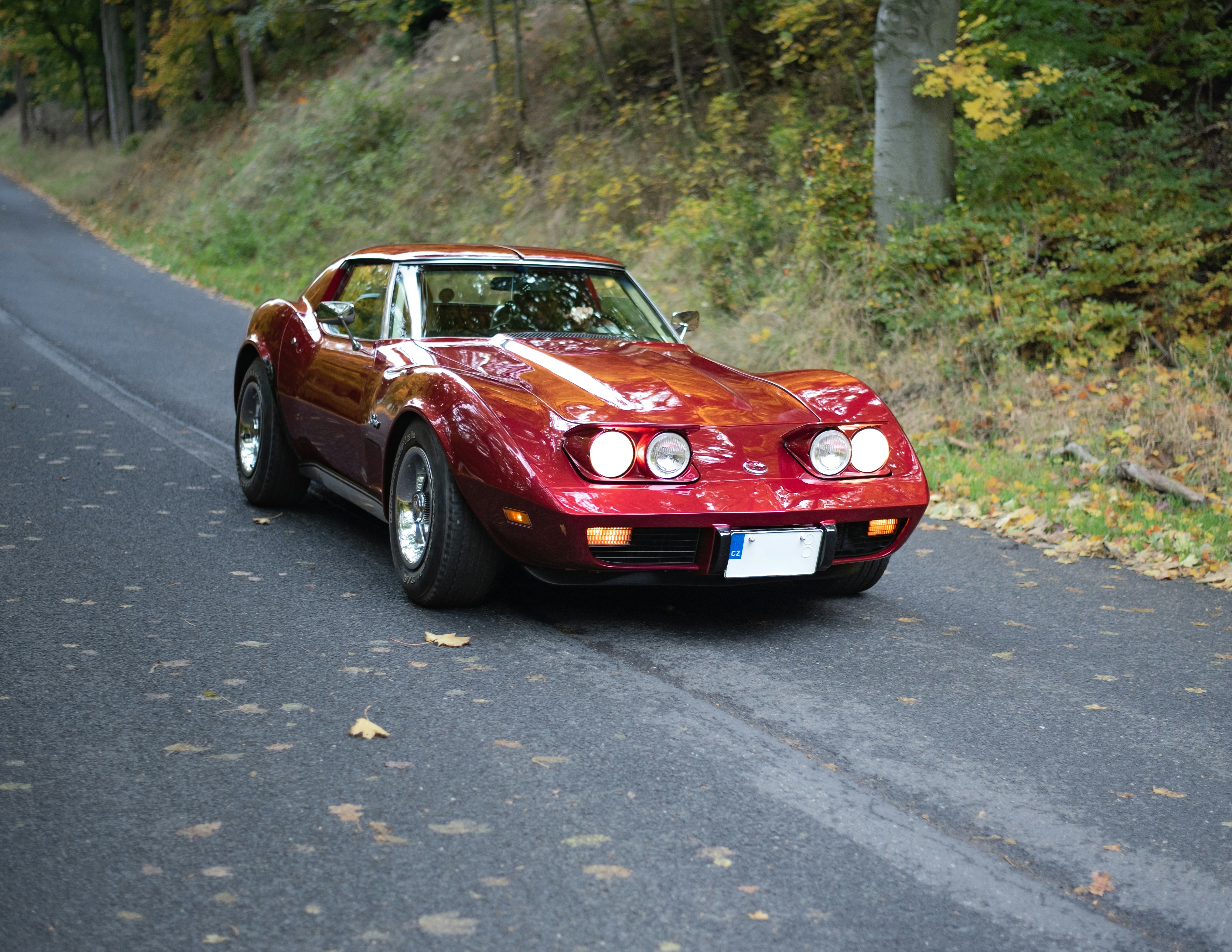 田舎道を運転する赤いビンテージコルベット