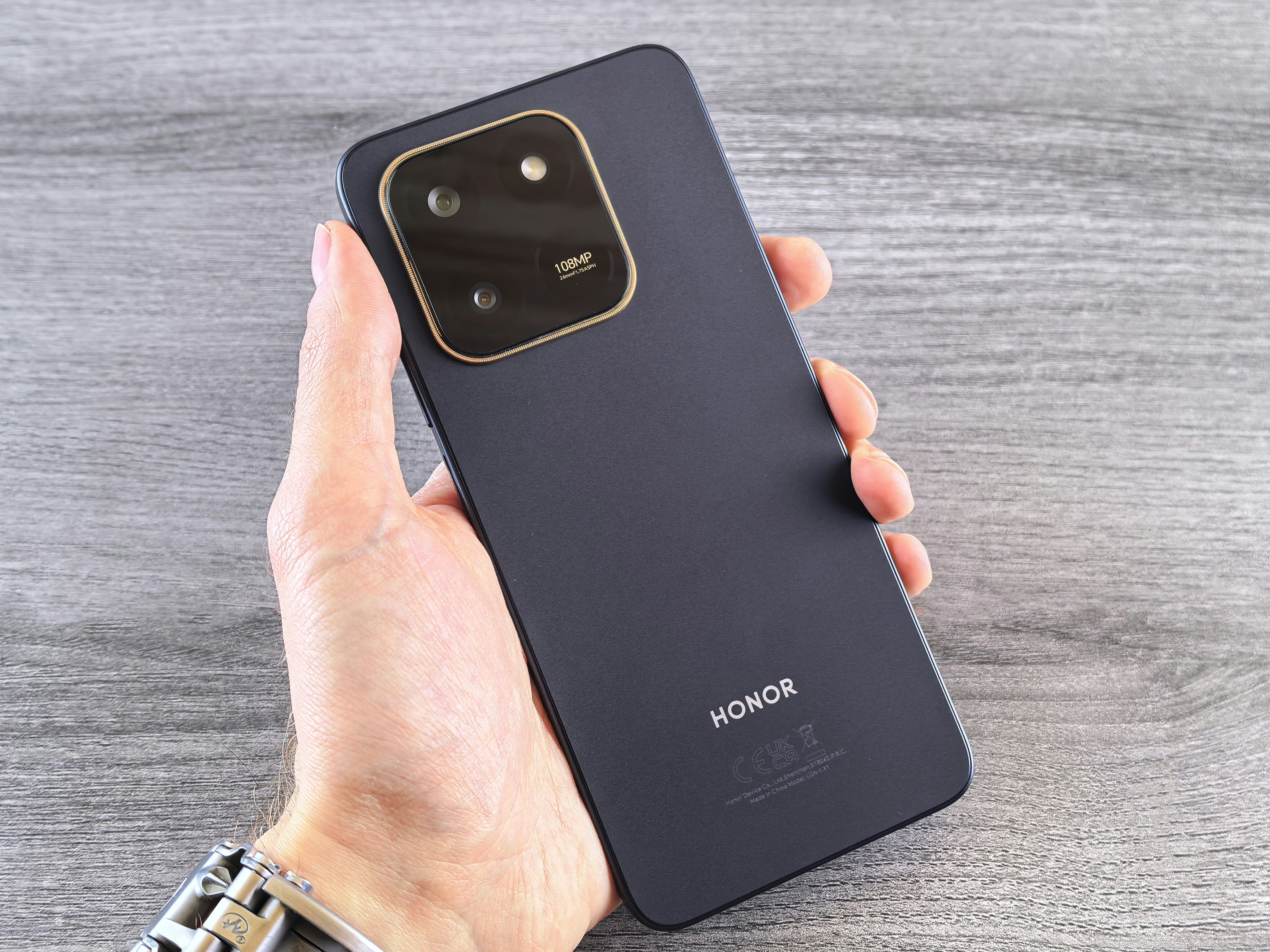 Hand holding a dark blue smartphone with camera module.