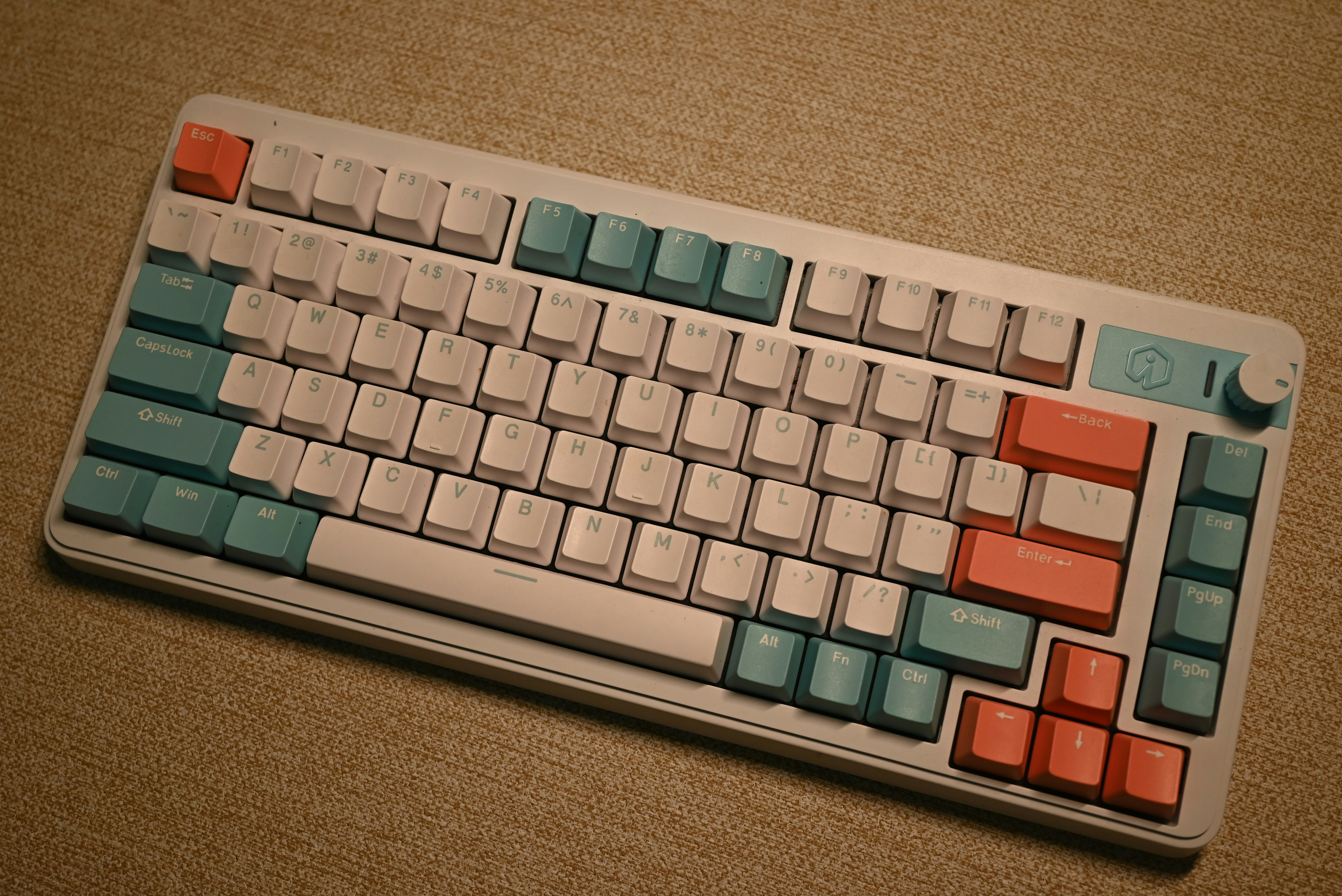 A mechanical keyboard with white, teal, and coral keycaps