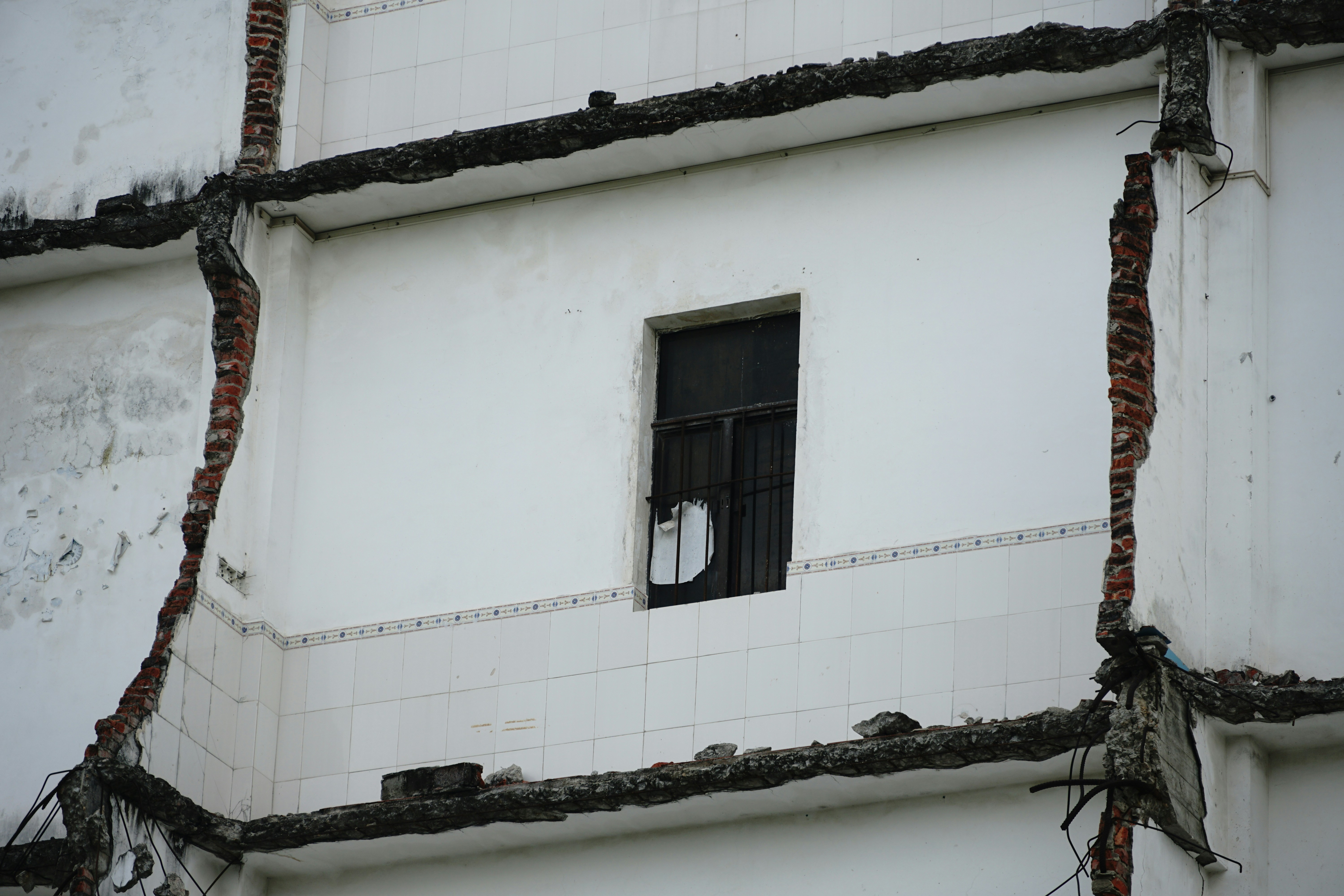 Prédio parcialmente demolido com uma única janela.